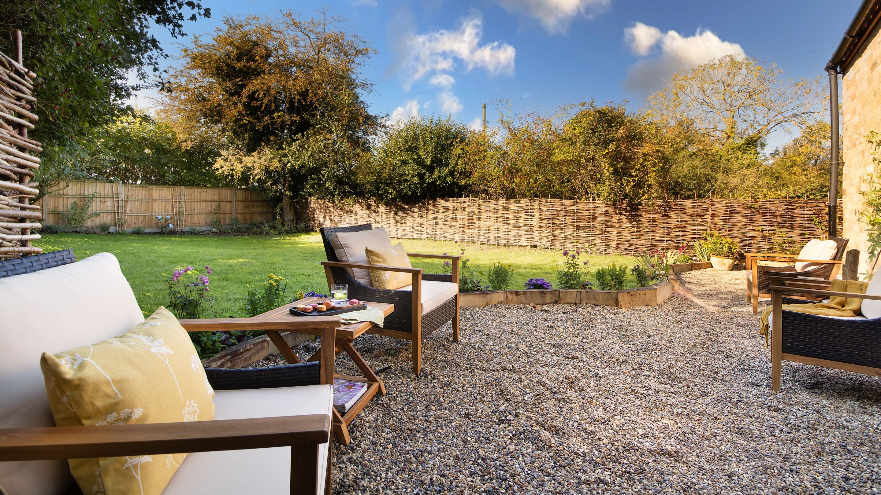 The back garden at Cladium, with a lawn, gravel patio and outdoor armchairs, Cambridgeshire