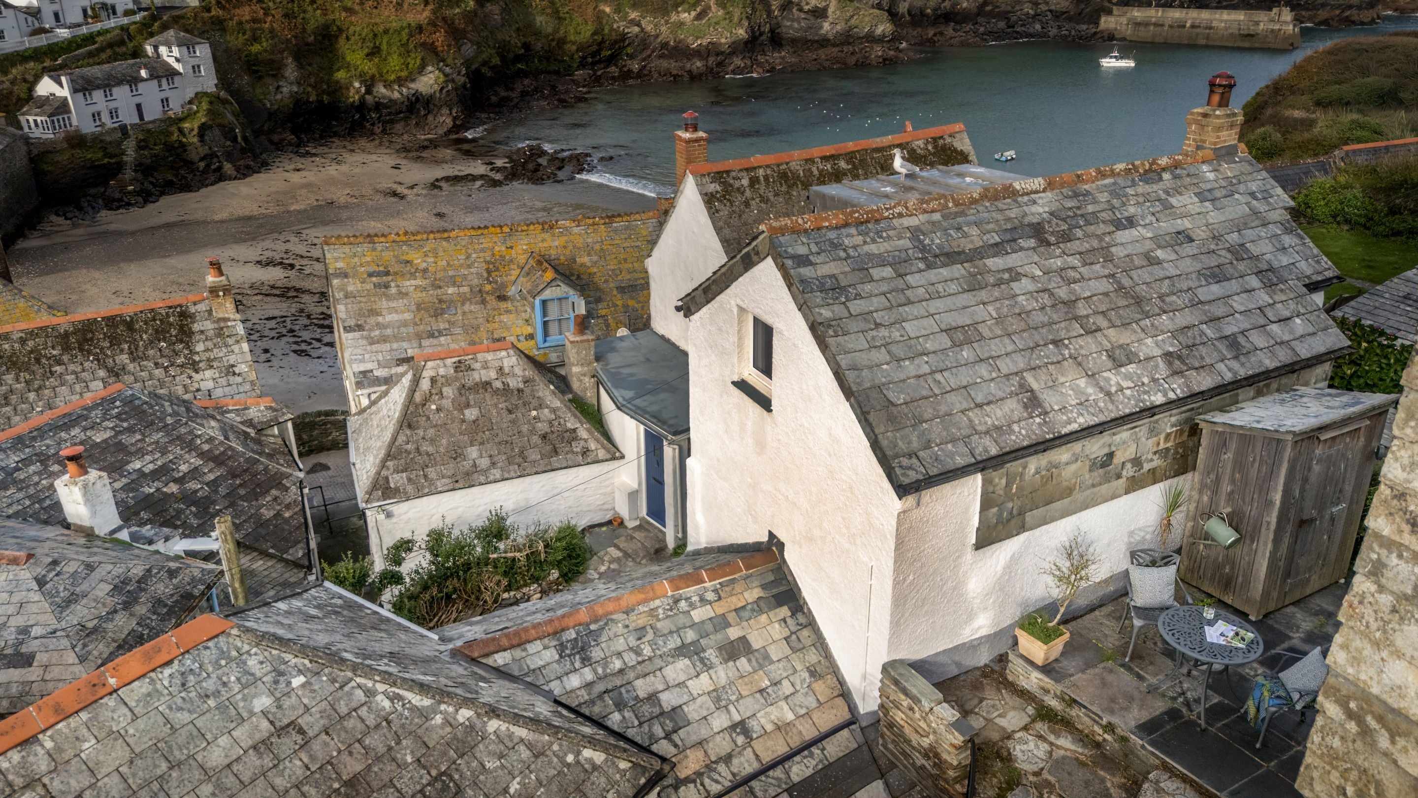An aerial view of the terrace at The Birdcage and the houses and beach of Port Isaac below, Cornwall