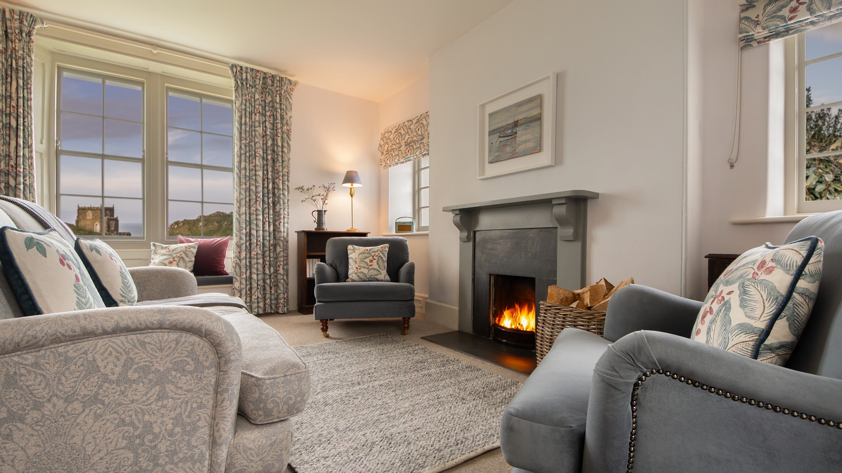 The open-plan sitting and dining room at Carnweather, with open fire and views of Doyden Castle, Cornwall