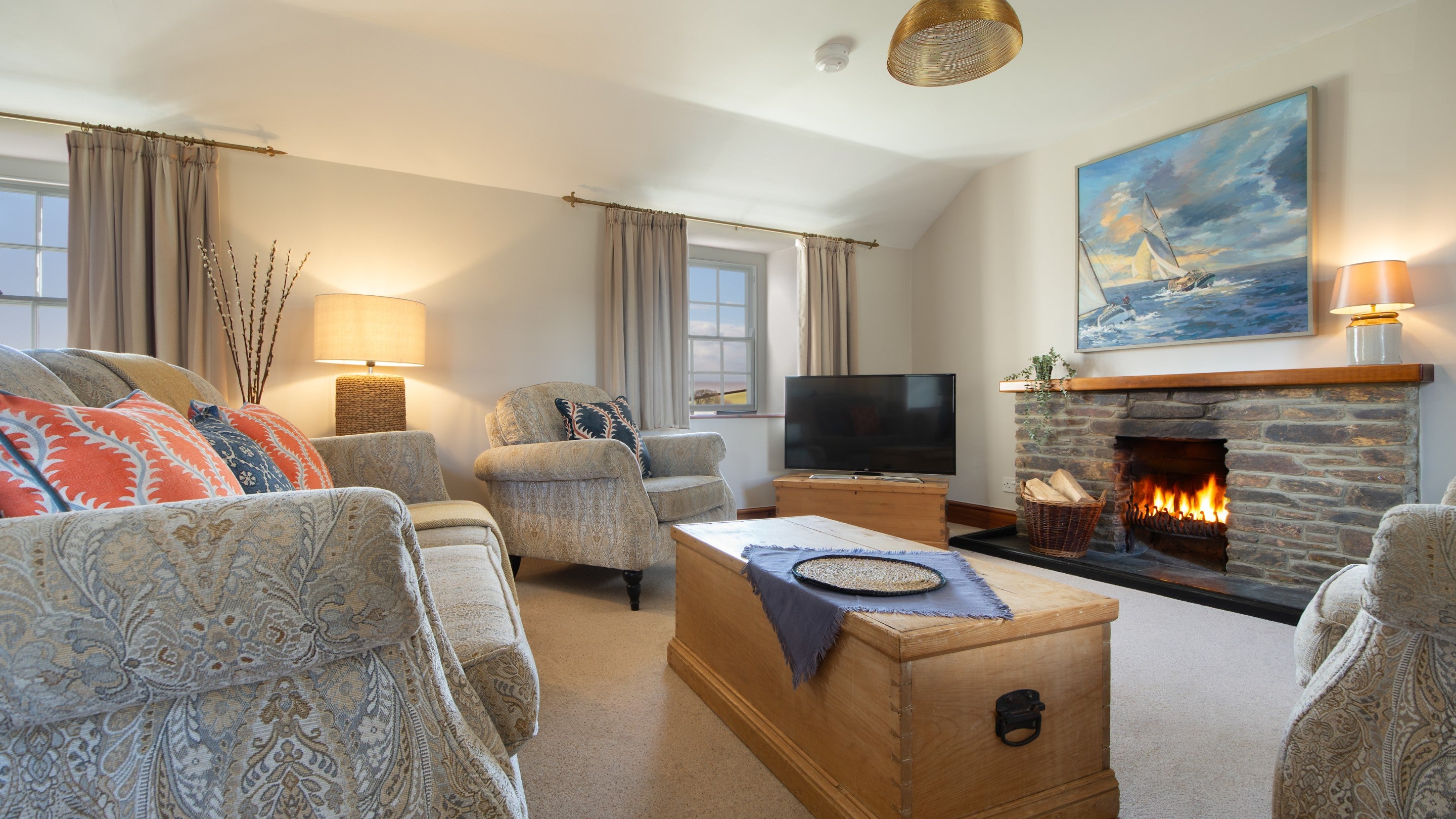 The open-plan dining and sitting room with open fire at Chenhalls Barn, Cornwall