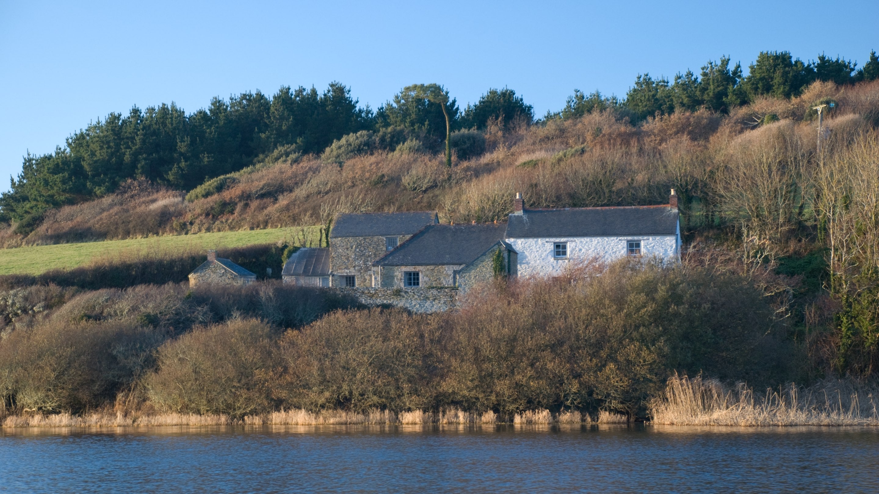 A view of Degibna Lower Pentire Farm House from across Loe Pool, Cornwall