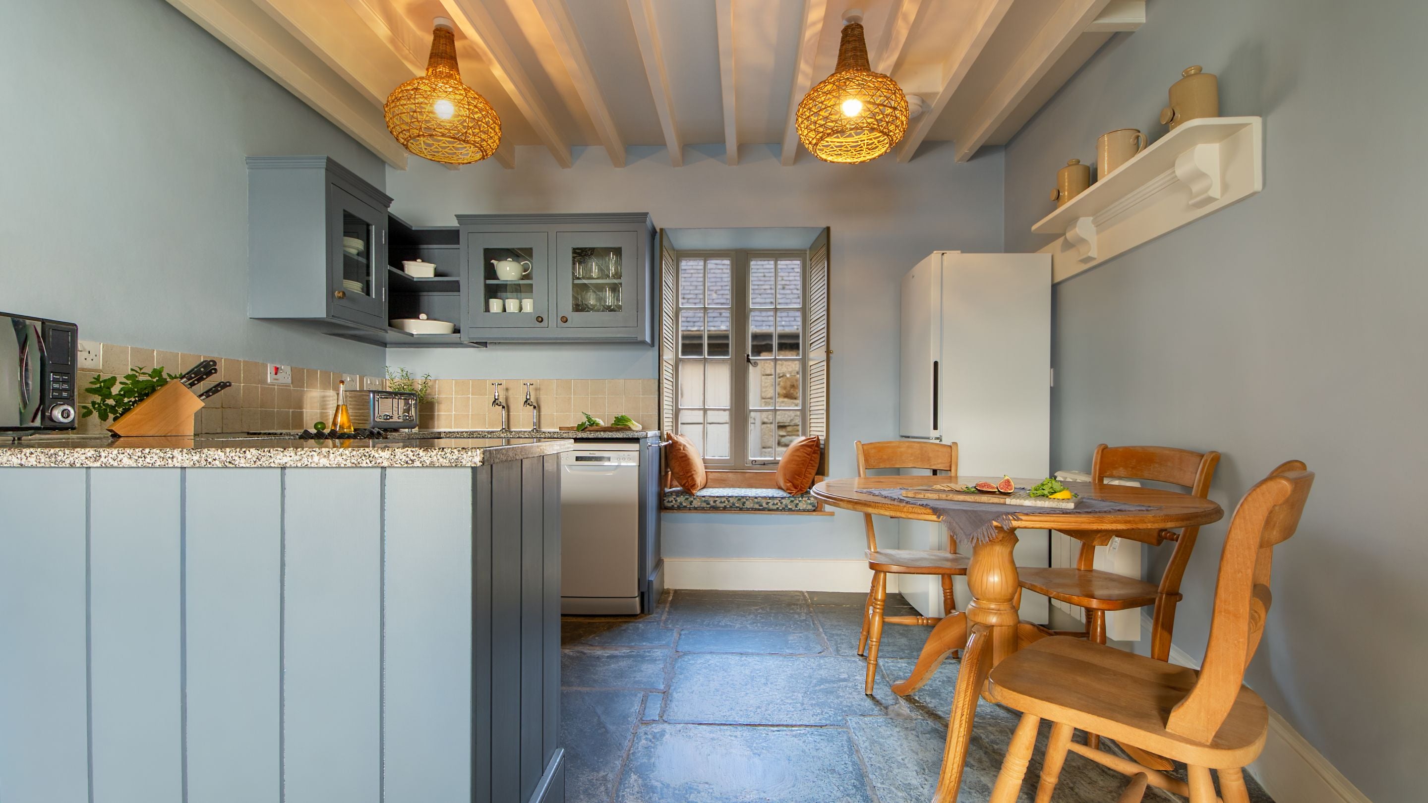 The kitchen area with a table for three at Durgan Quay Cottage, Cornwall