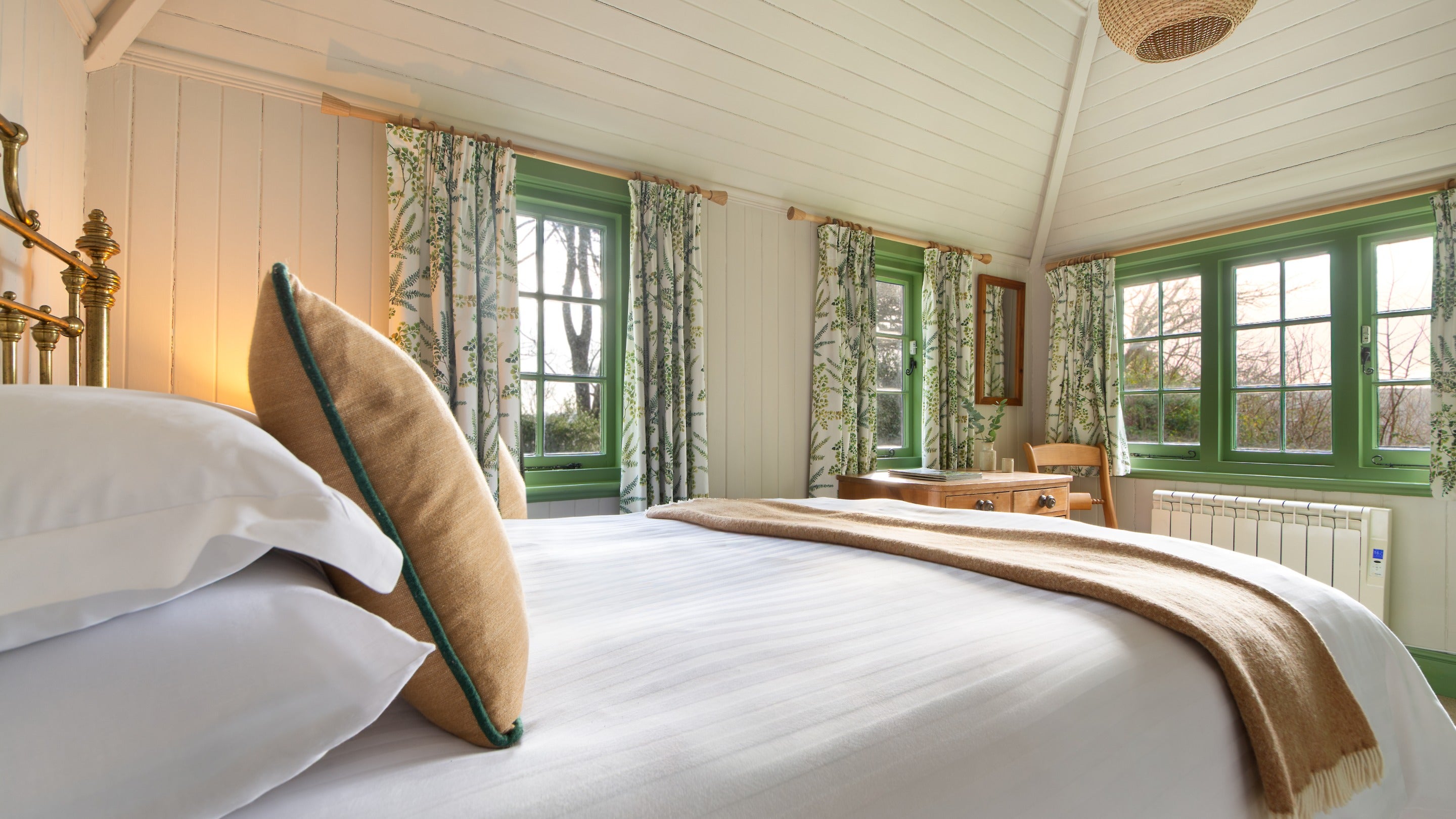 The double bedroom at Durgan Wood Cottage with three large windows, Cornwall