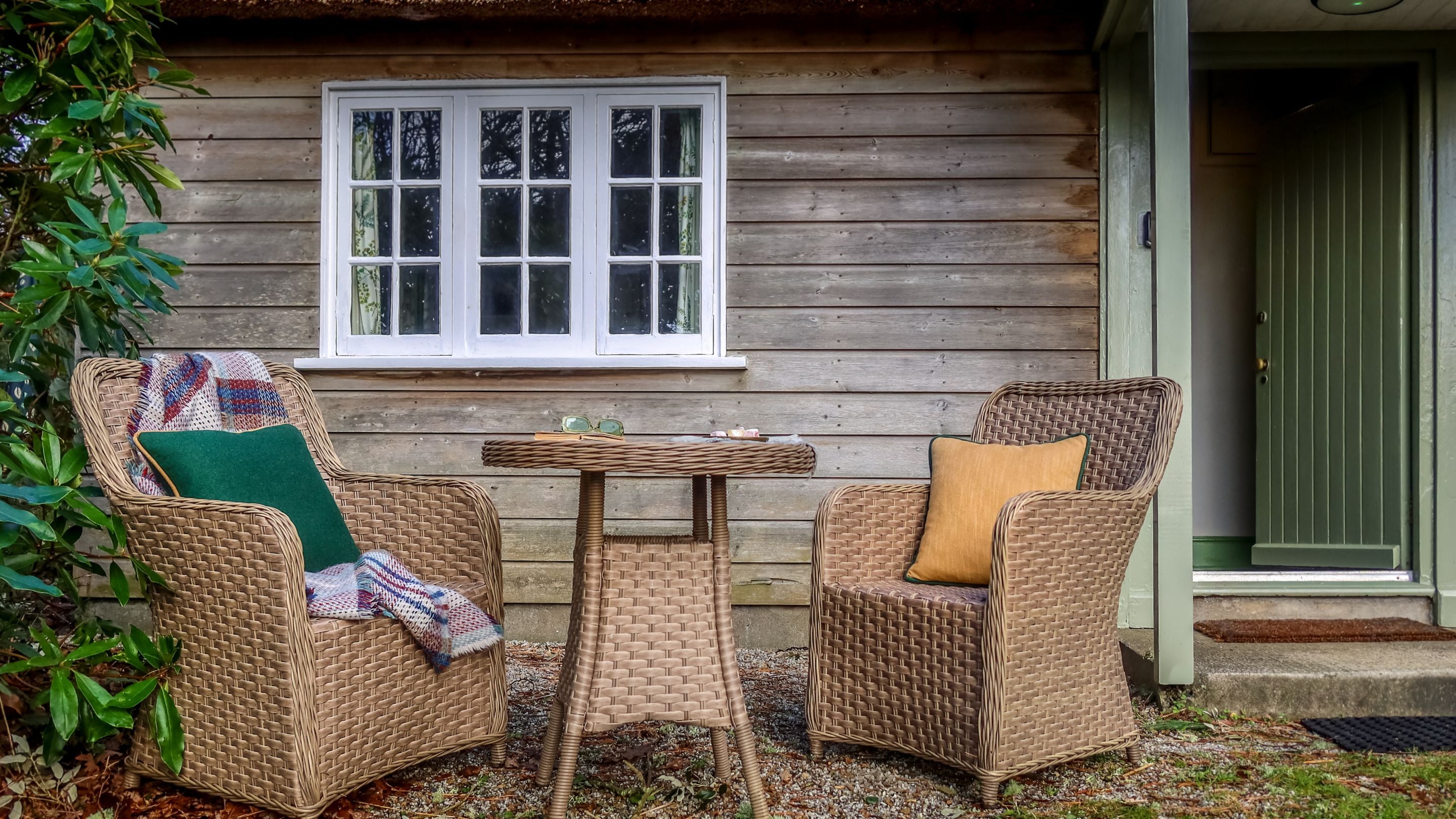 Outdoor chairs and table on a small gravelled area in front of Durgan Wood Cottage, Cornwall