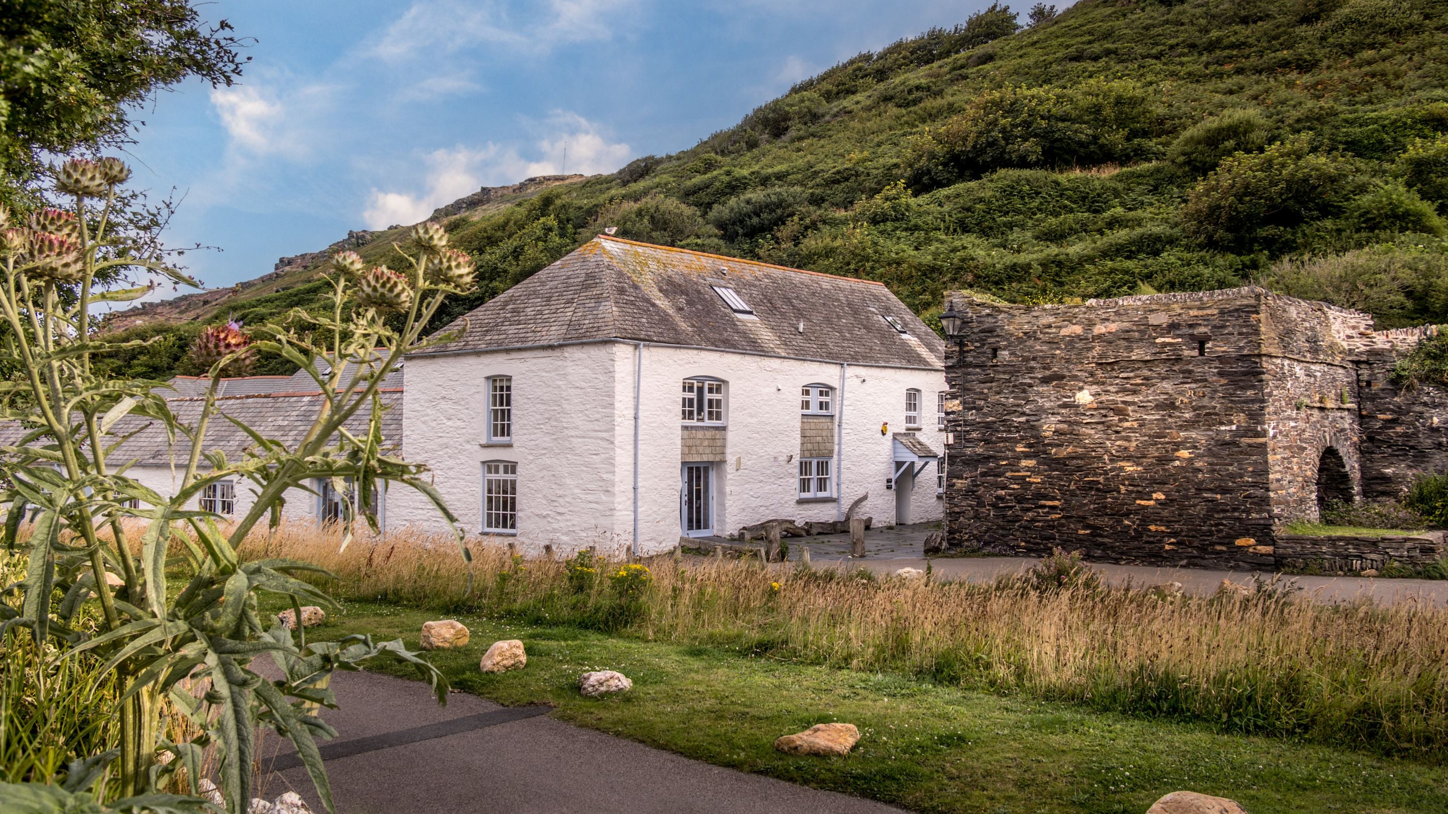 The National Trust building in Boscastle, with the entrance to The Gaffer and The Clinker down the lane, closest to the lime kiln wall, Cornwall