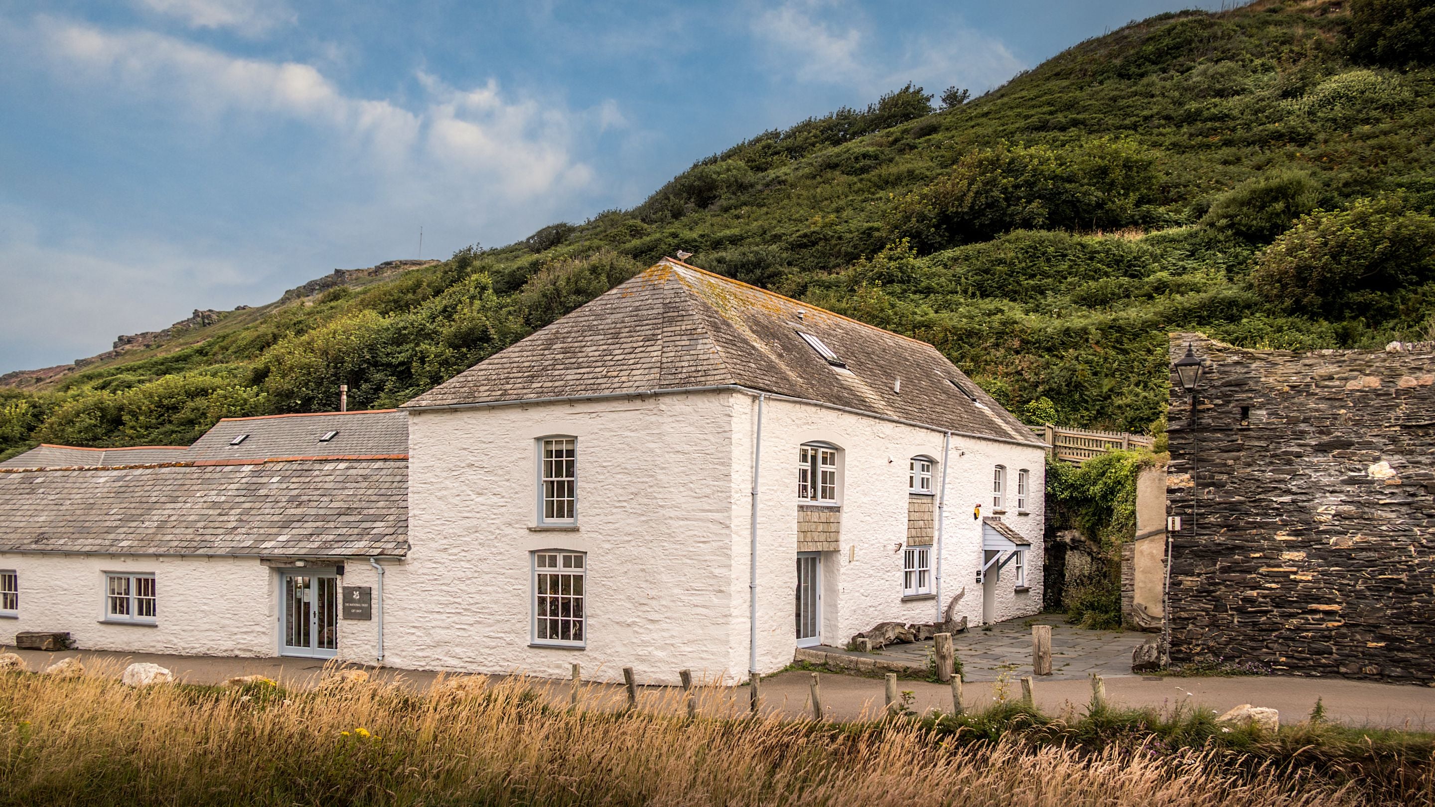 The National Trust building in Boscastle, with the entrance to The Gaffer and The Clinker down the lane, closest to the lime kiln wall, Cornwall