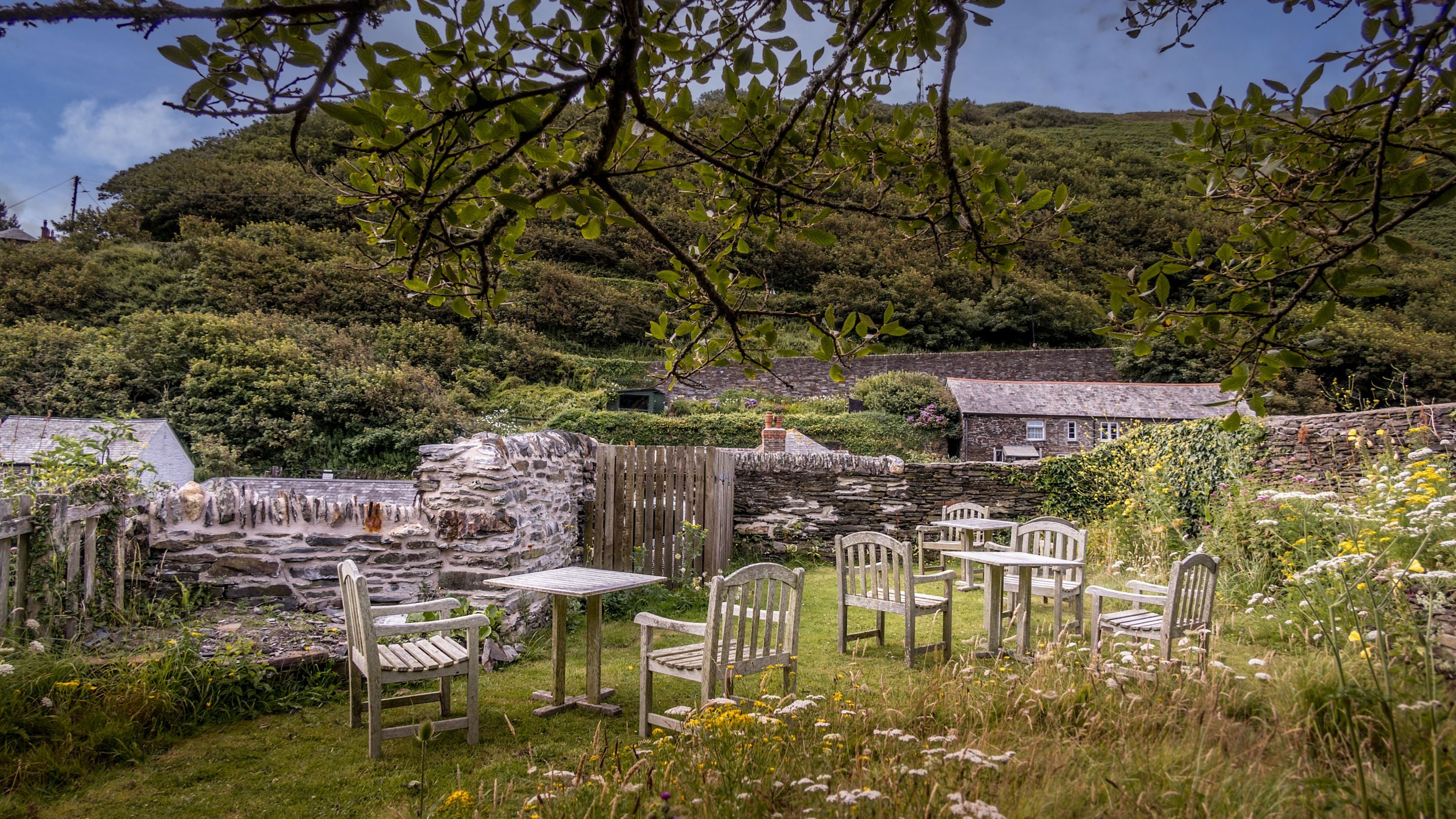 The shared garden of The Gaffer, The Clinker and The Lugger, with outdoor tables and chairs. It is an enclosed, lawned garden with shrubs, on top of old lime kiln, opposite the apartments, Cornwall