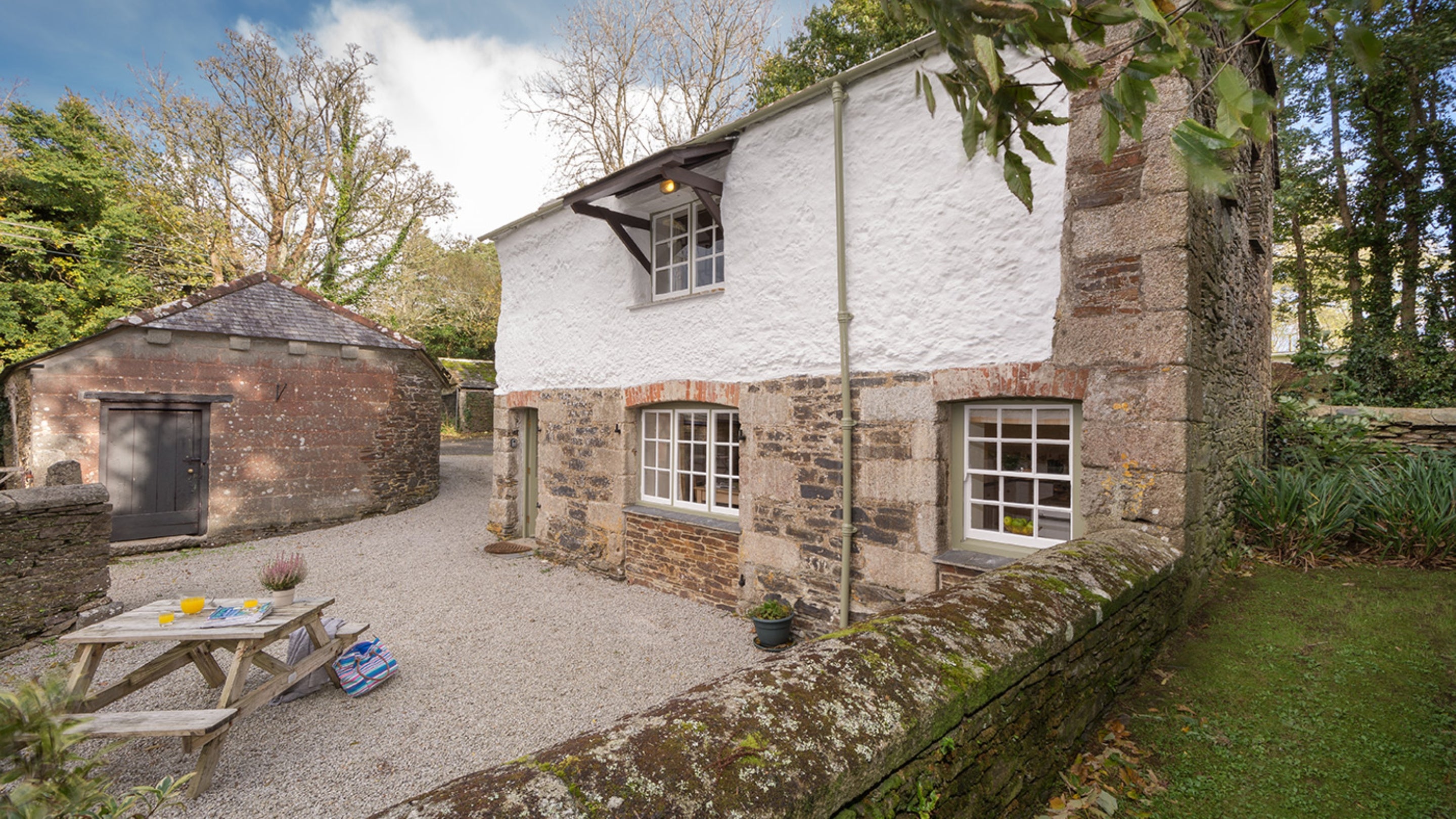 Glebe Cottage and part of its garden, which is gravelled and has a picnic bench, Cornwall