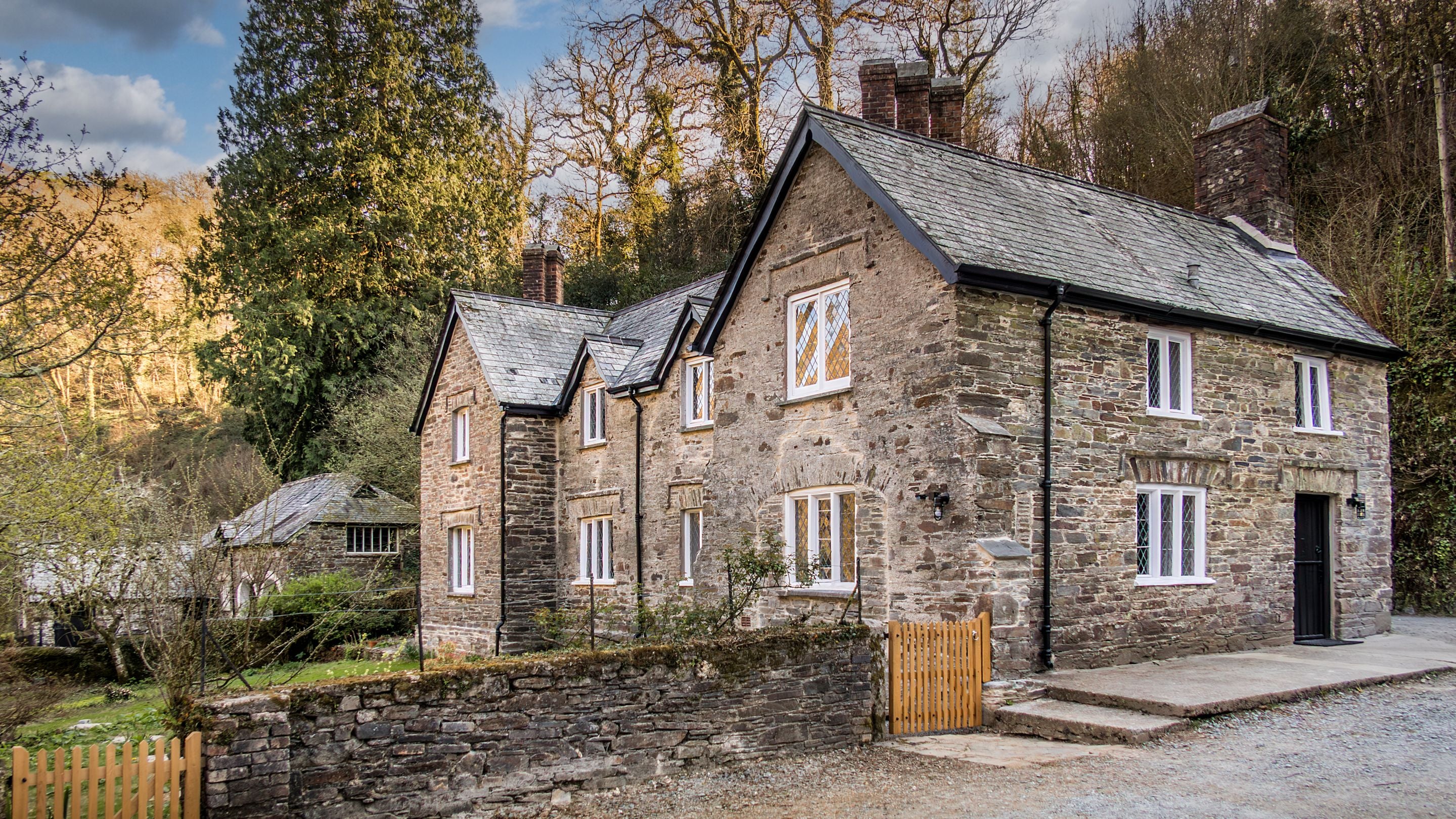 The side and back of Miller's House, a large slatestone cottage with grassy garden, Cornwall