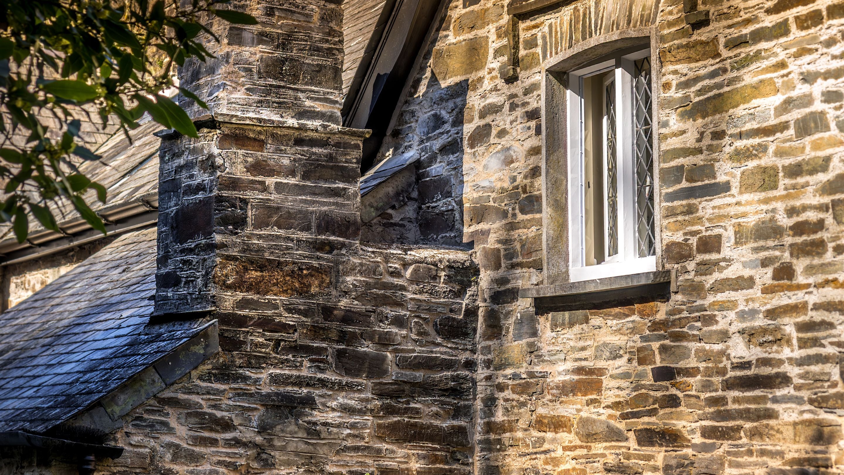 The slatestone walls of Miller's House, with uneven grey and brown stones and cream mortar, Cornwall
