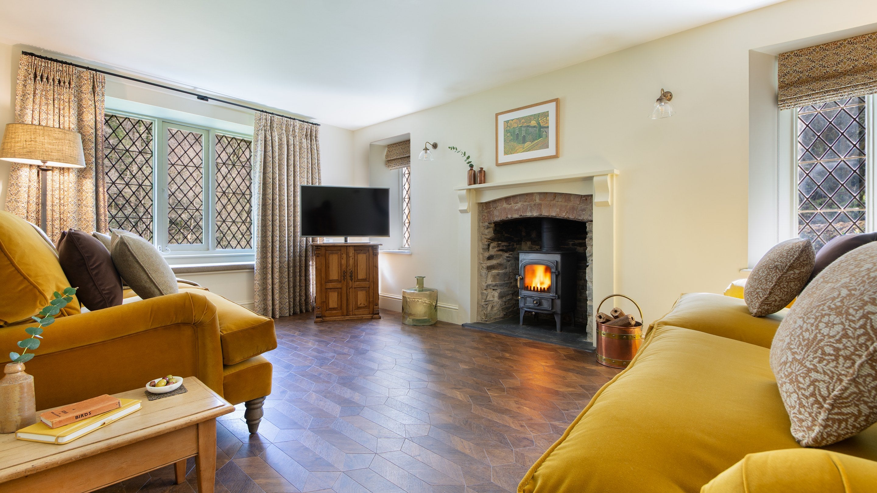 The sitting room with sofas, television, window seat and woodburner at Miller's House, Cornwall