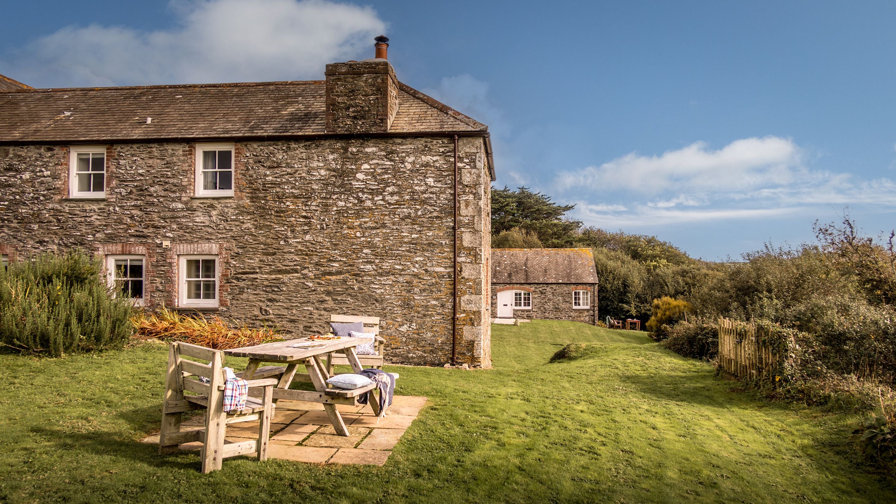 The exterior of Mowhay and the shared garden, with lawn and outdoor dining furniture, Cornwall