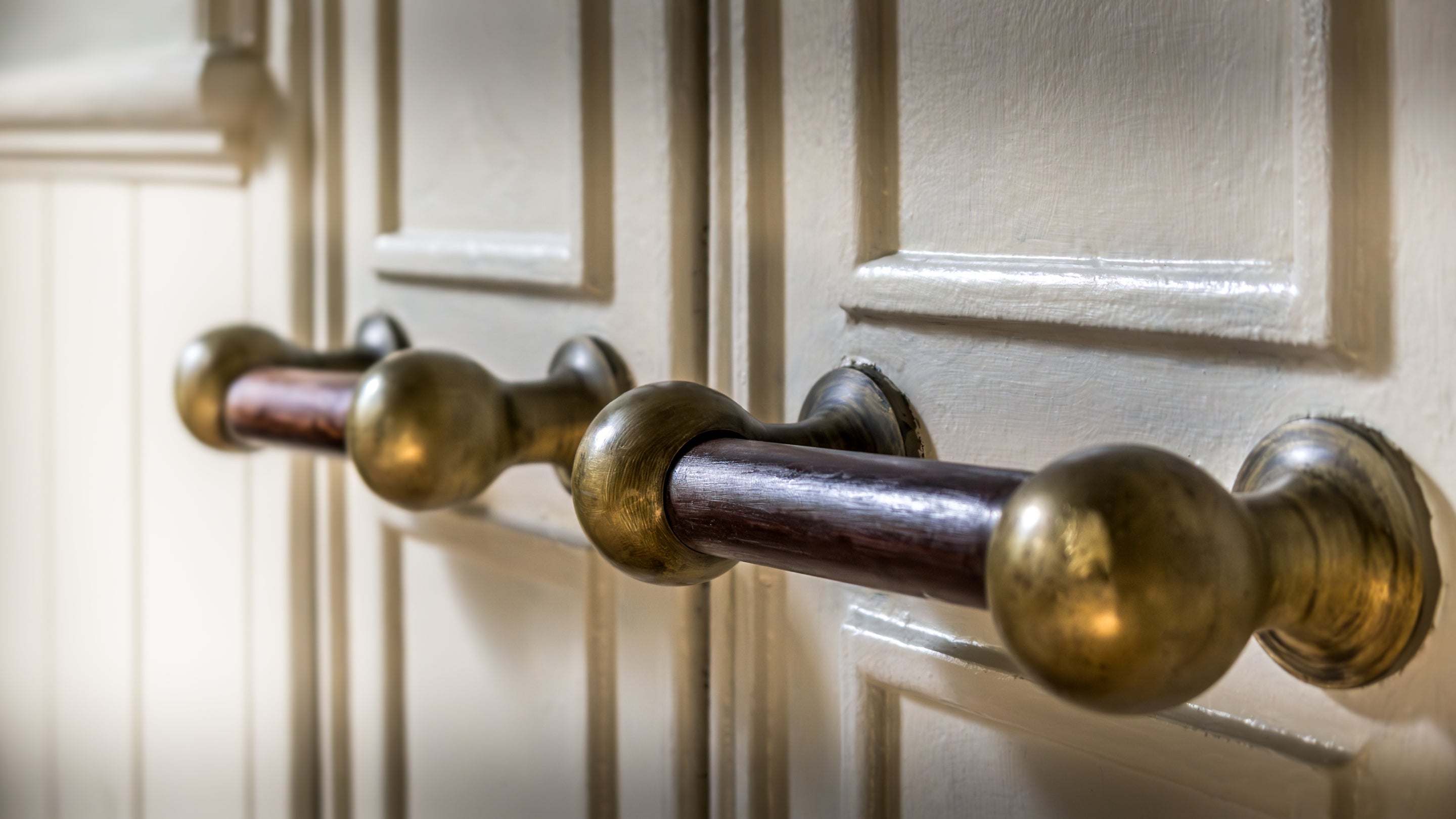 Brass and wood handles on the original laundry doors in the sitting room at Nanceglos House, Cornwall