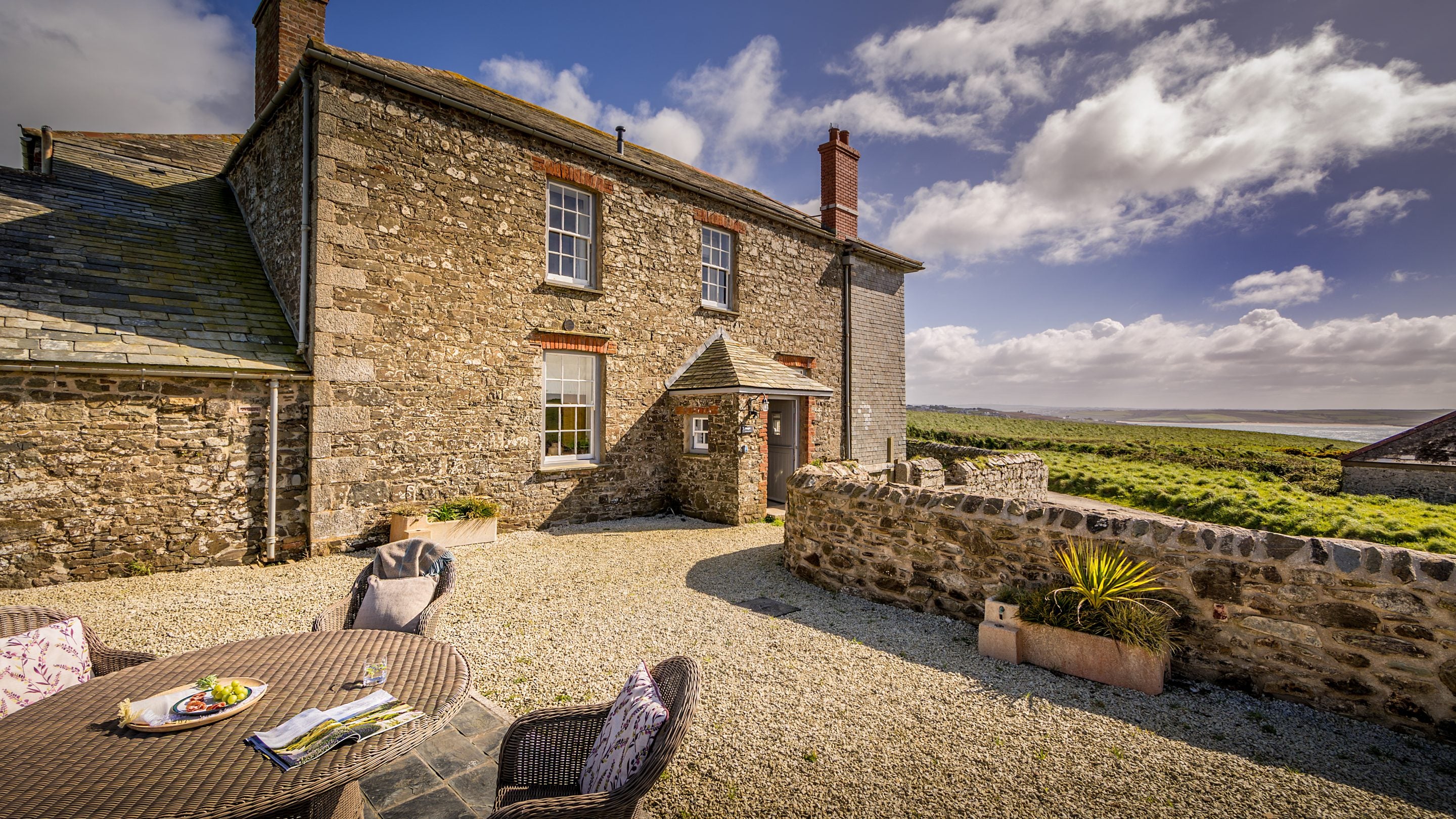 The front of Pengirt, with table and chairs on the gravelled terrace, Cornwall