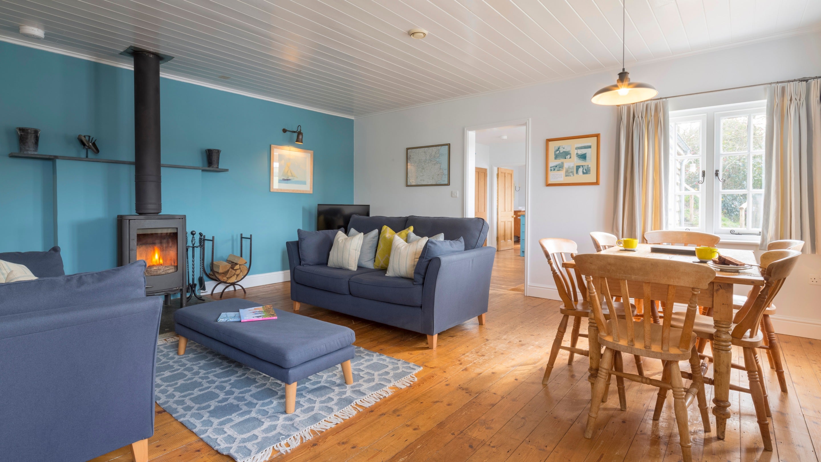 The sitting and dining room at Powders, with sofas, woodburner and dining table and chairs for six, Cornwall