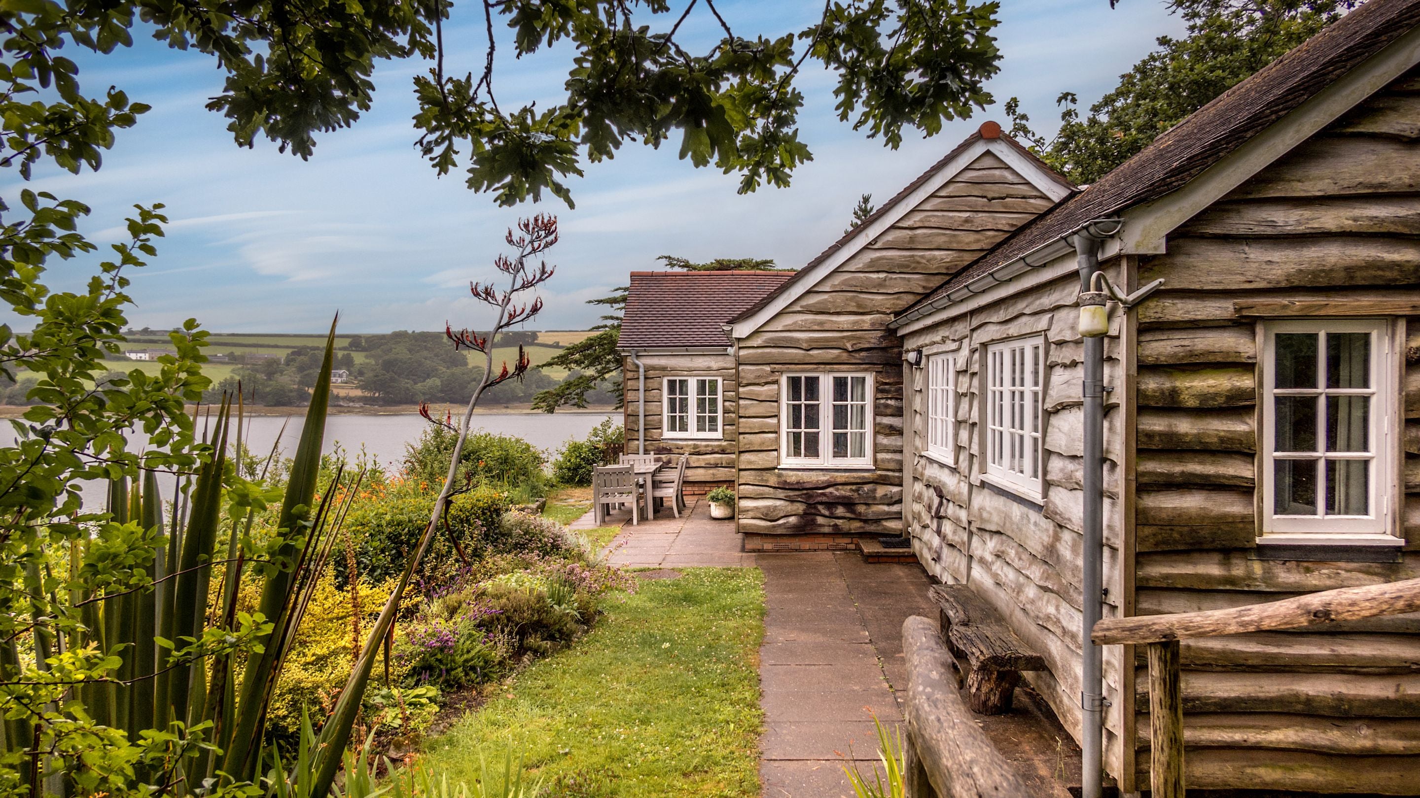 The exterior of Powders and its garden, with the Helford River in the background, Cornwall