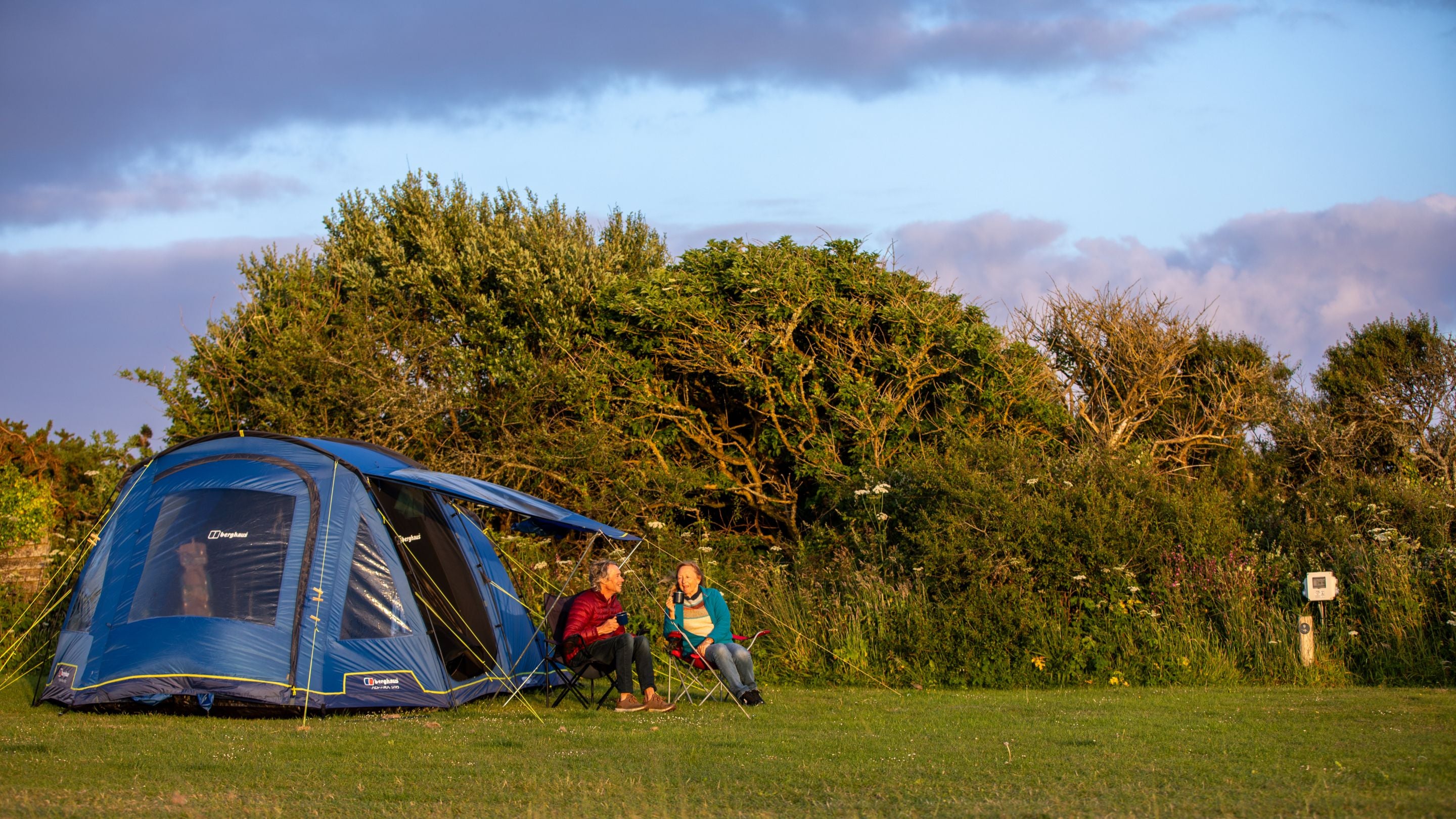 Campers sat outside their tent at Teneriffe Farm Campsite, Cornwall
