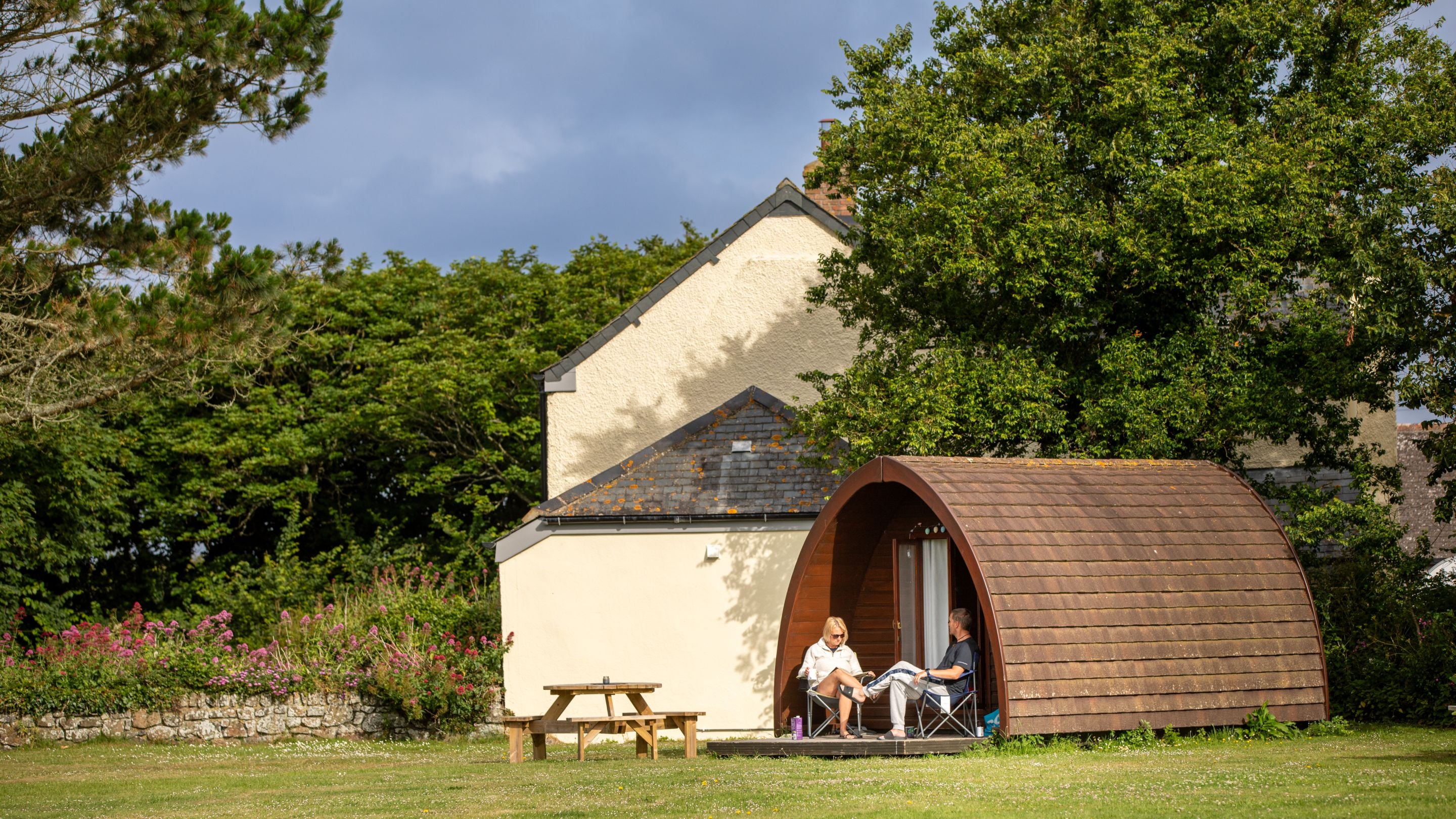 Guests sat outside their pod at Teneriffe Farm Campsite, Cornwall