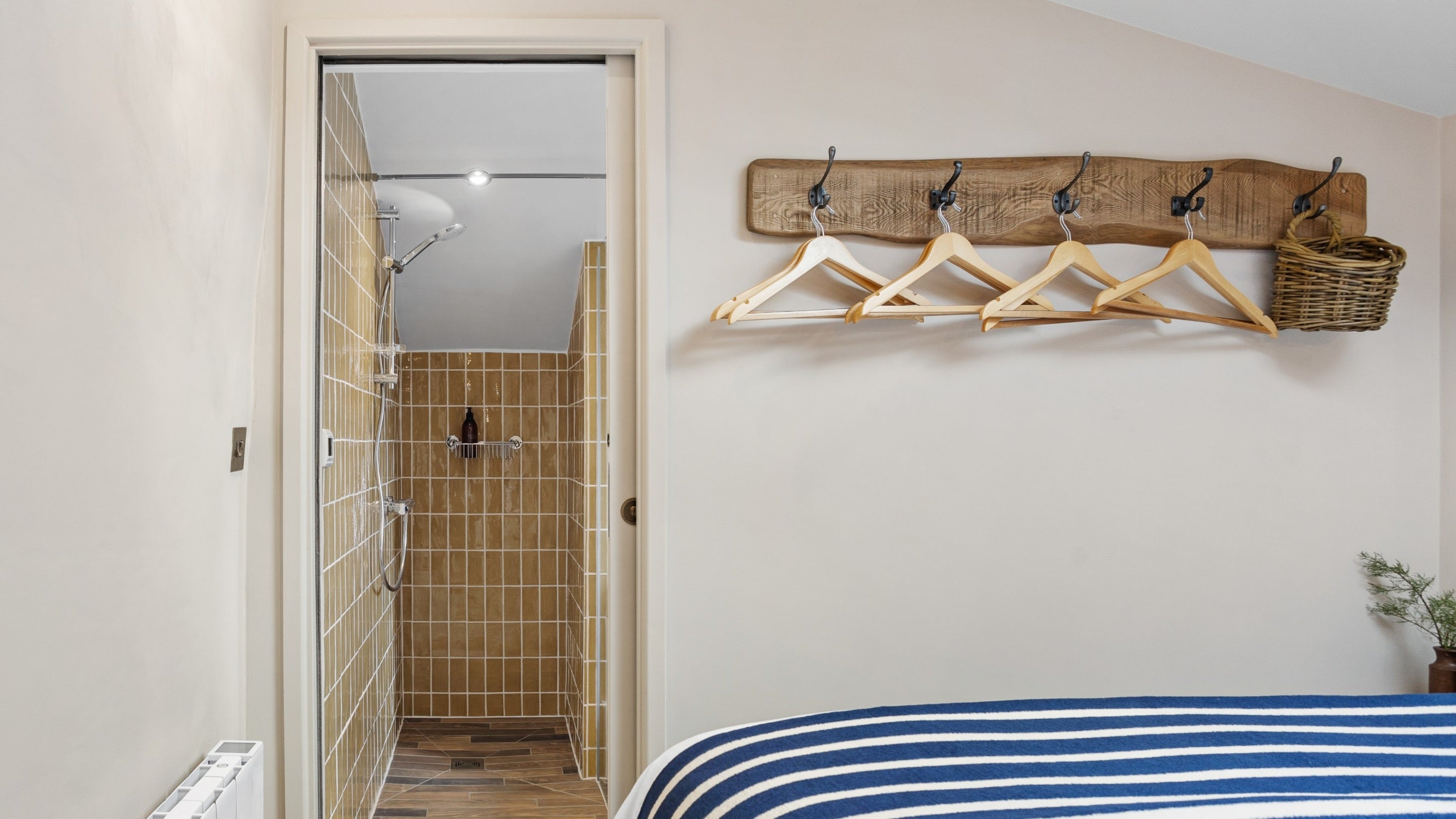 The bedroom, with coat hooks for storage, and en-suite shower room at Tom Parsons' Hut, Cornwall