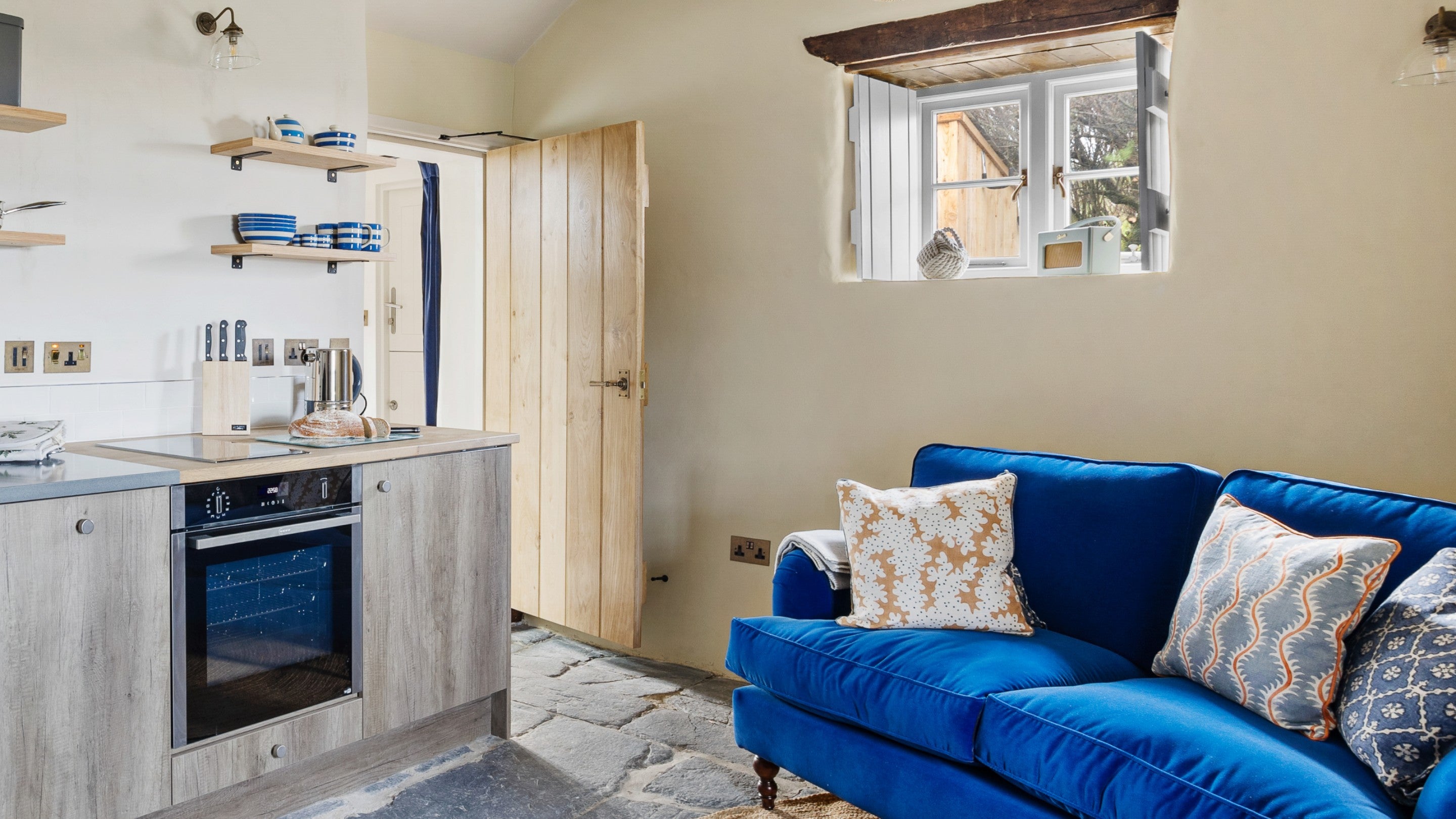 A view of the open-plan living space at Tom Parsons' Hut, showing part of the kitchen and the sofa, Cornwall