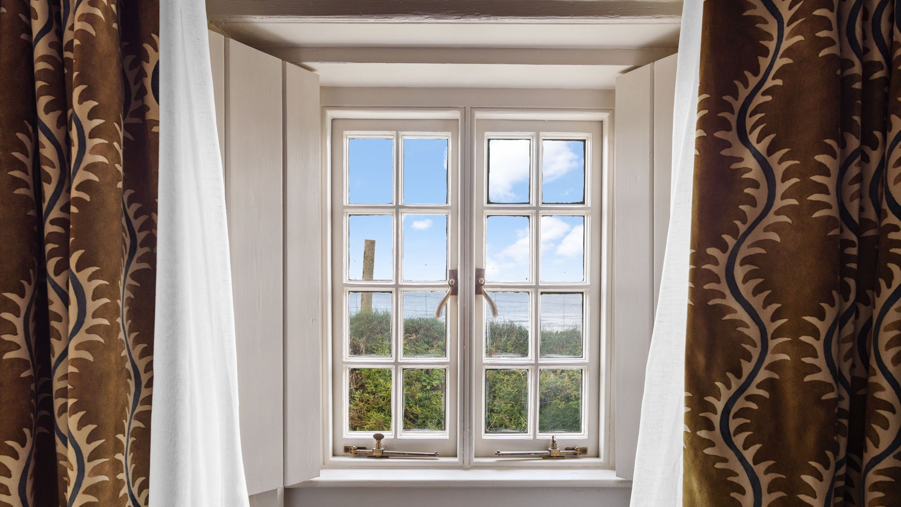 The window with sea views, above the table for two in the living space at Tom Parsons' Hut, Cornwall