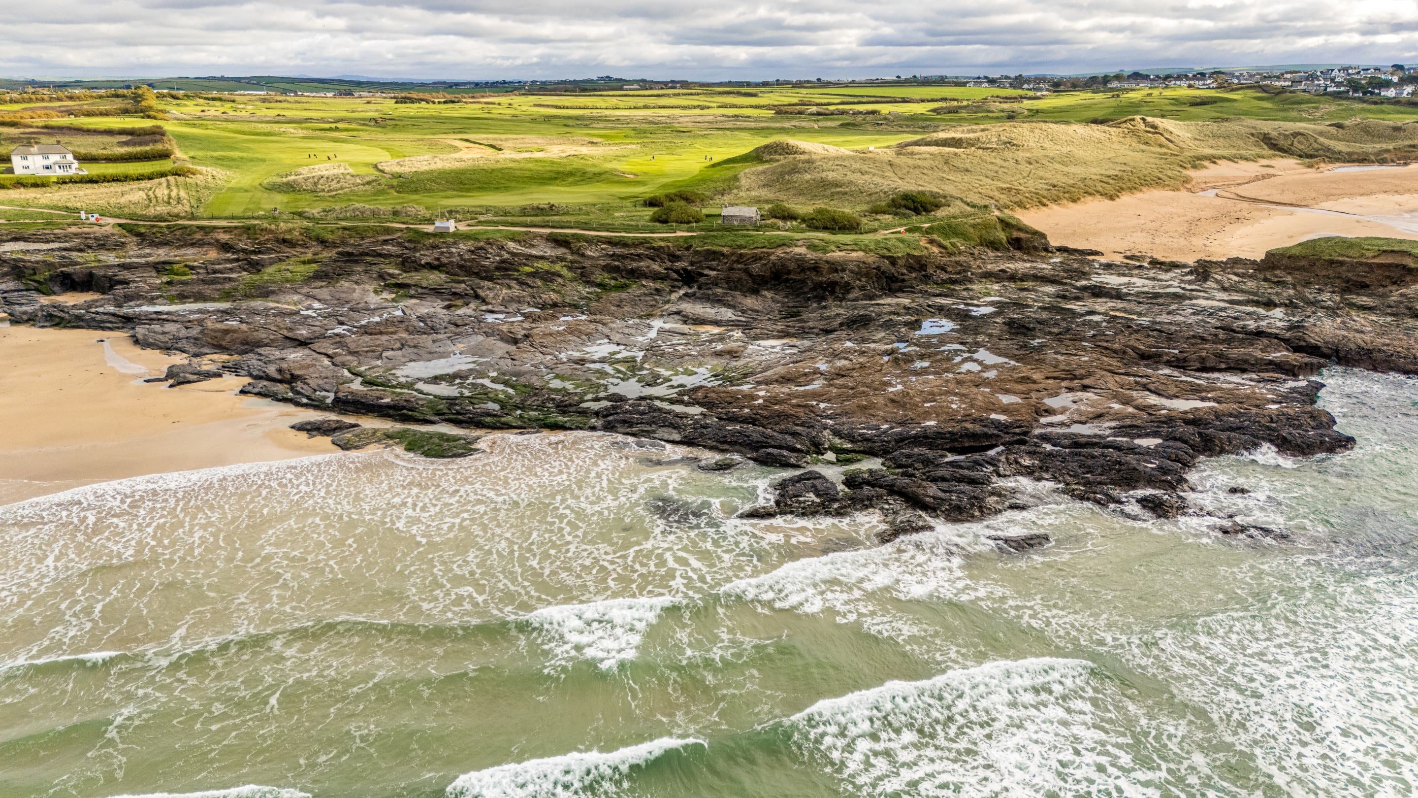 An aerial view looking inland to Tom Parsons' Hut, with Booby's Bay beach on the left, Constantine Bay beach on the right, and the golf course behind the cottage, Cornwall