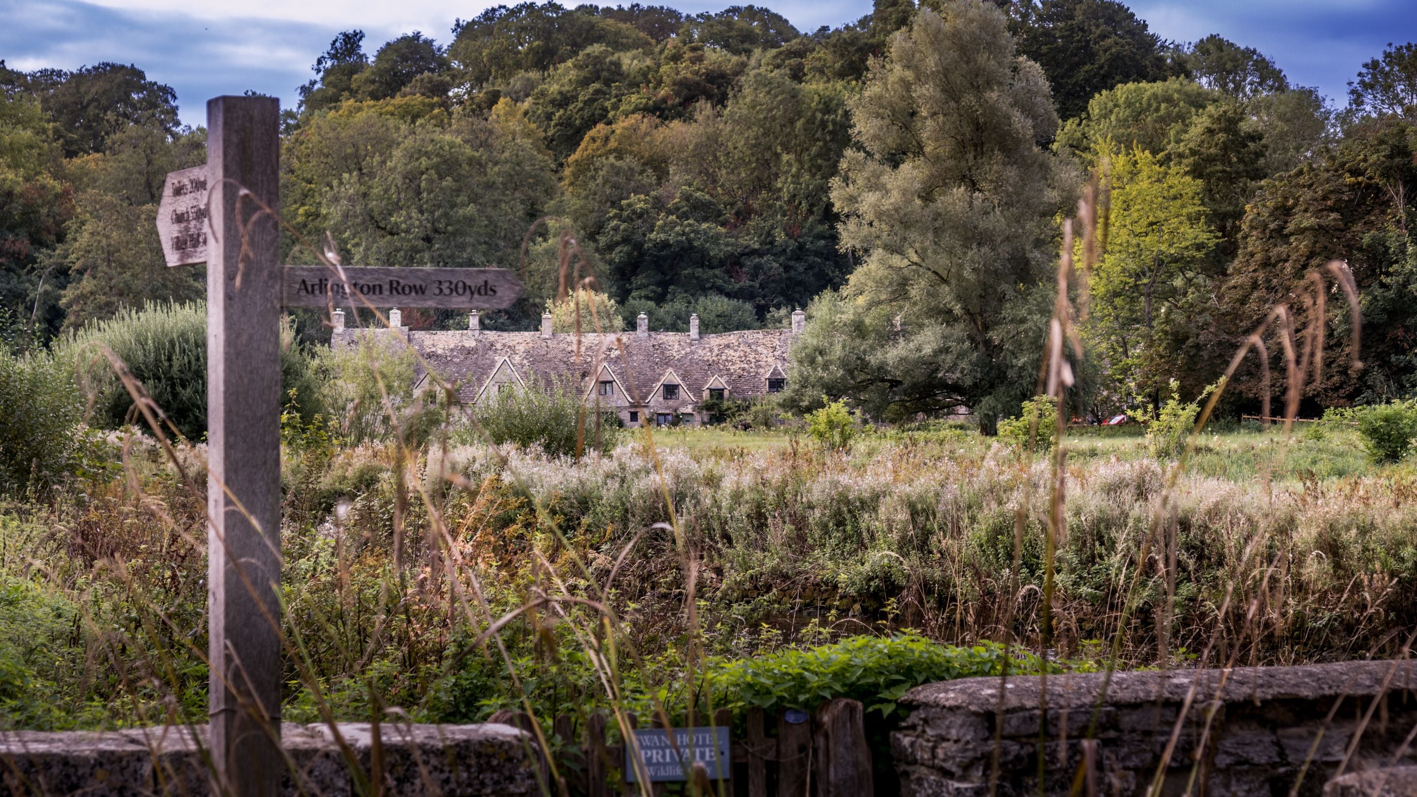 The footpath sign for Alrington Row, with the terrace in the background, Gloucestershire