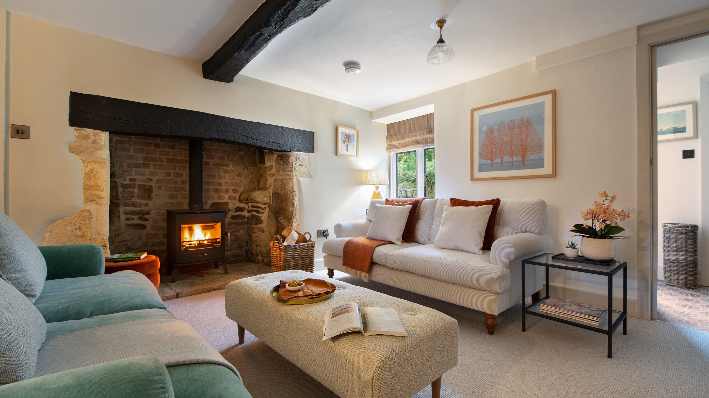 The open-plan sitting and dining room, with original beams and inglenook, and woodburner at 1 Arlington Row, Gloucestershire