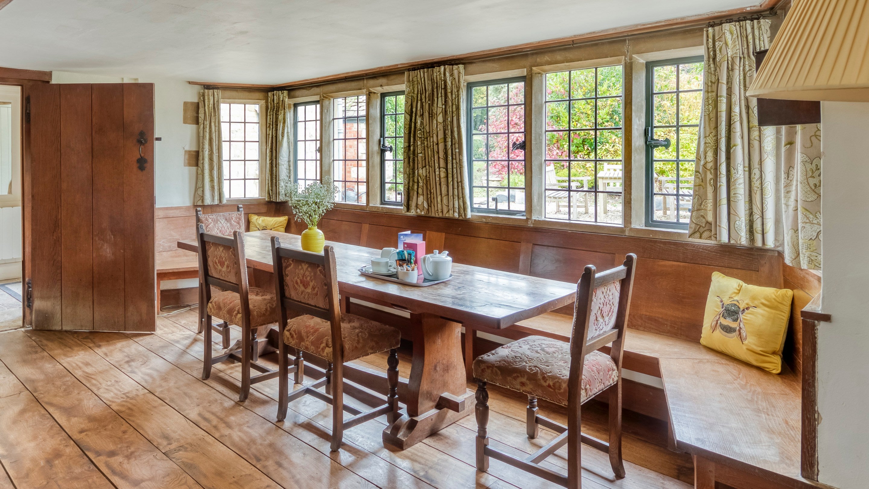The dining table with bench seating in a large bay window at The Little Fleece, Gloucestershire