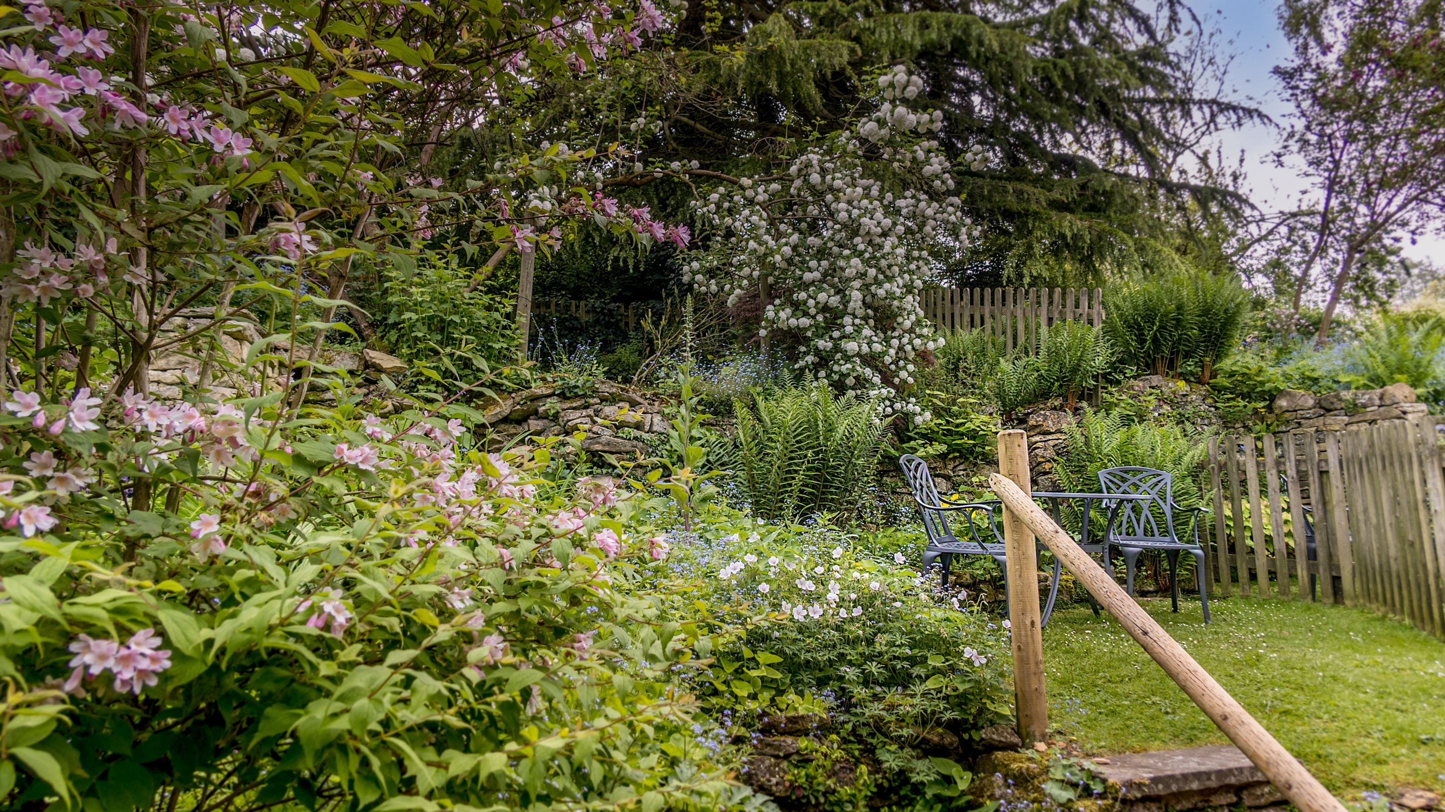 The garden at Spring Cottage has steps up to the lawn and seating area, Gloucestershire