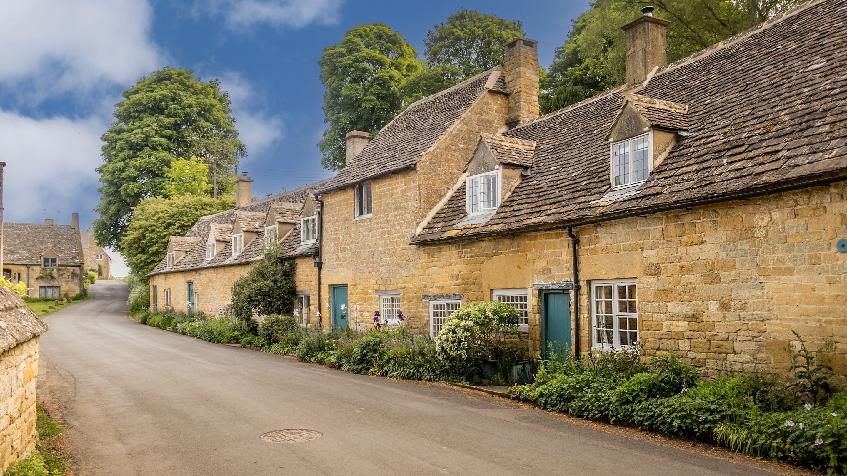 Looking along the village street at Spring Cottage and its neighbours in spring, Gloucestershire