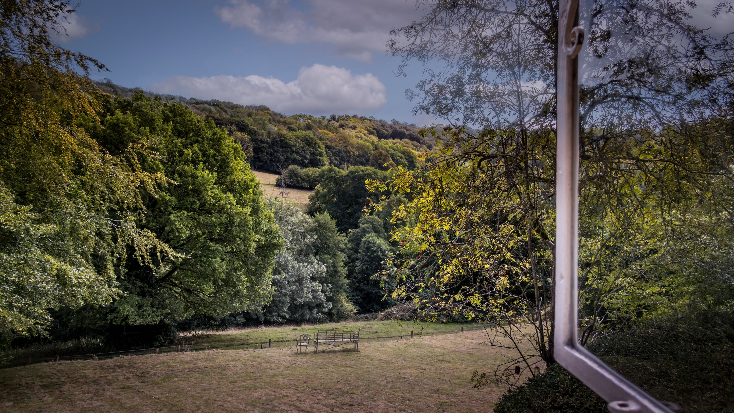 The view of the garden and woodland beyond from the super king-size bedroom's window at Woody's Cottage, Gloucestershire
