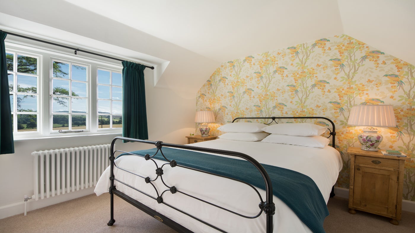 The double bedroom at Crabtree Lodge, Devon with double bed with yellow floral wallpaper behind it