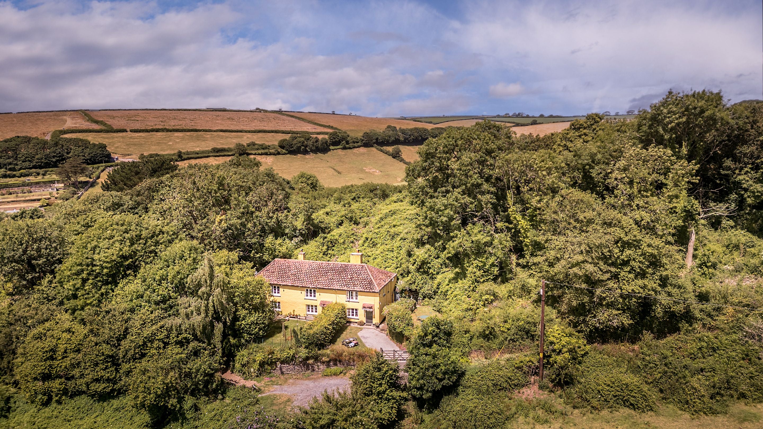 An aerial view of Crockers Cottage and the surrounding woodland and fields, Devon