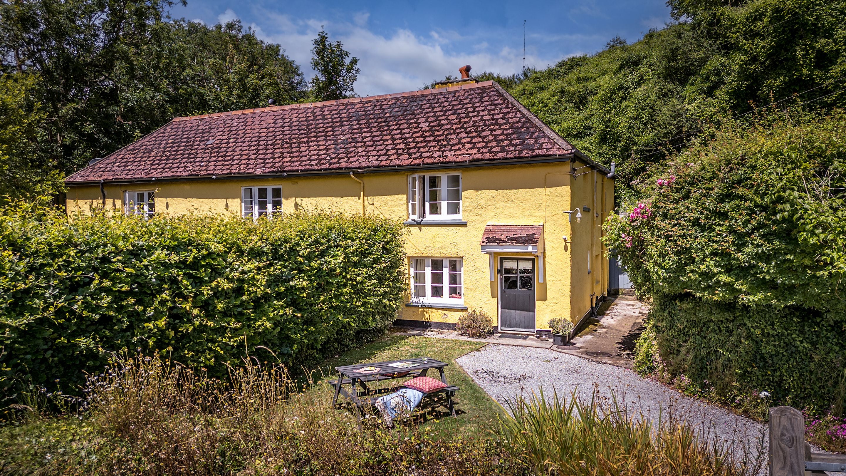 Crockers Cottage and its front garden, with driveway, lawn and picnic bench, Devon