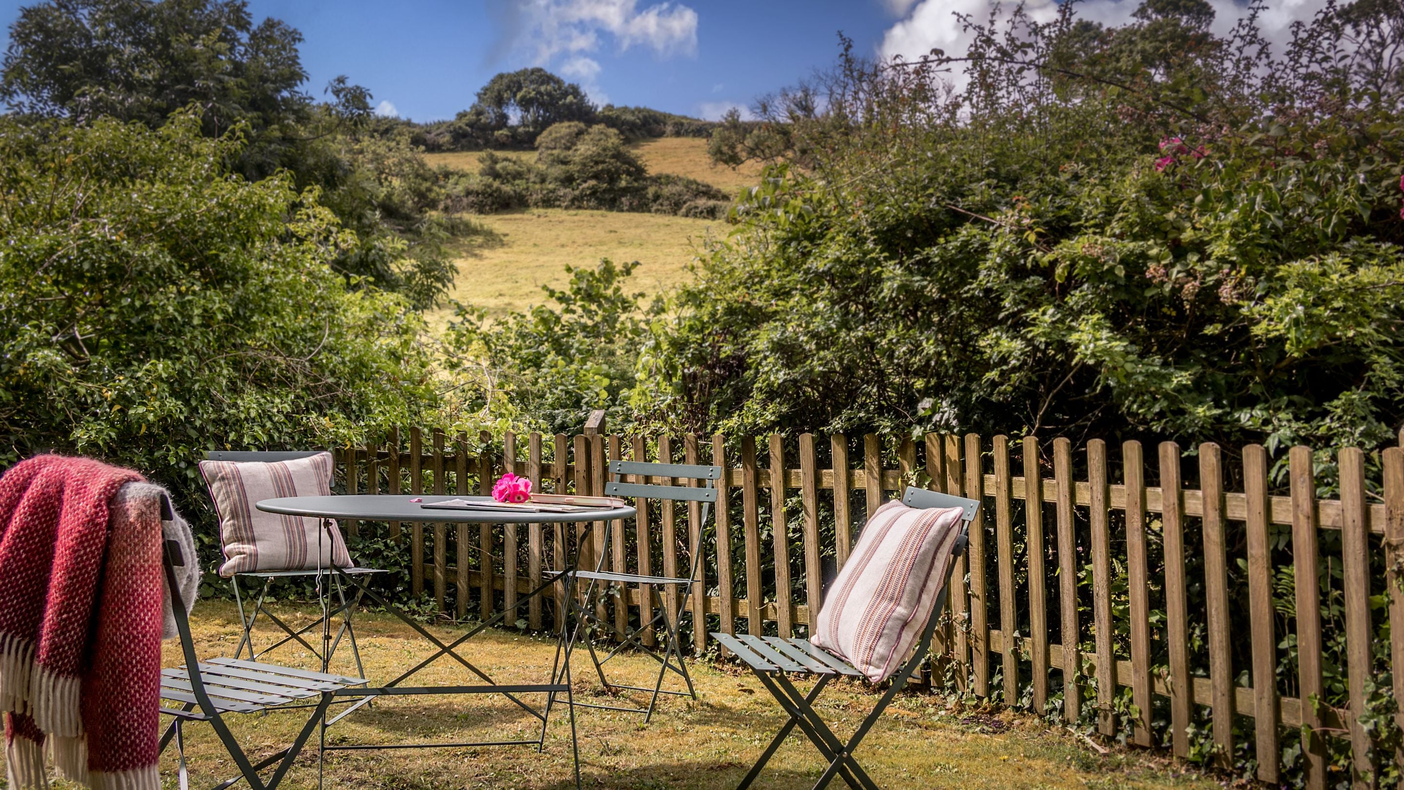 The side garden, with lawn, table and chairs at Crockers Cottage, Devon