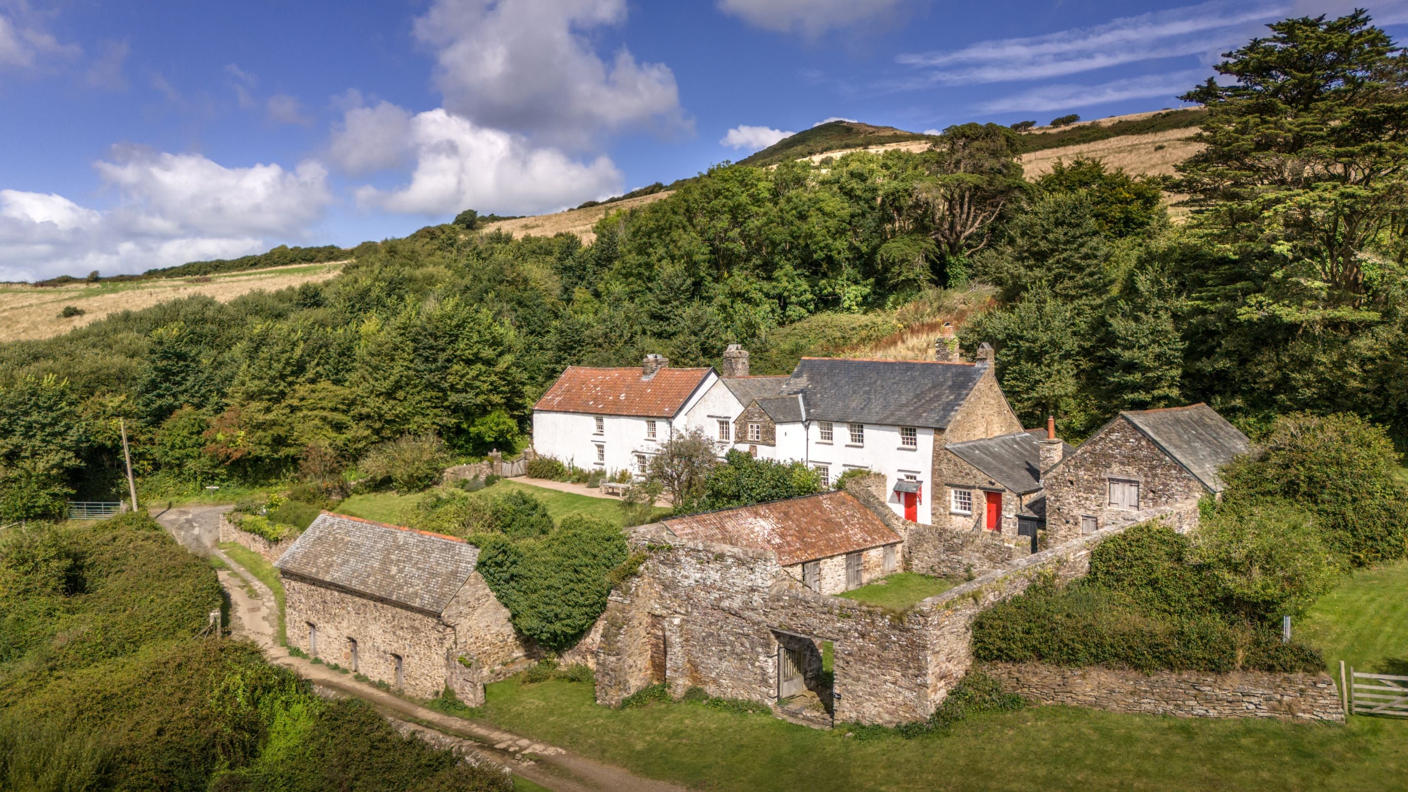 An aerial view of West Challacombe Manor and Cottage, including the grassy courtyard which takes you to the main entrance of the manor, Devon