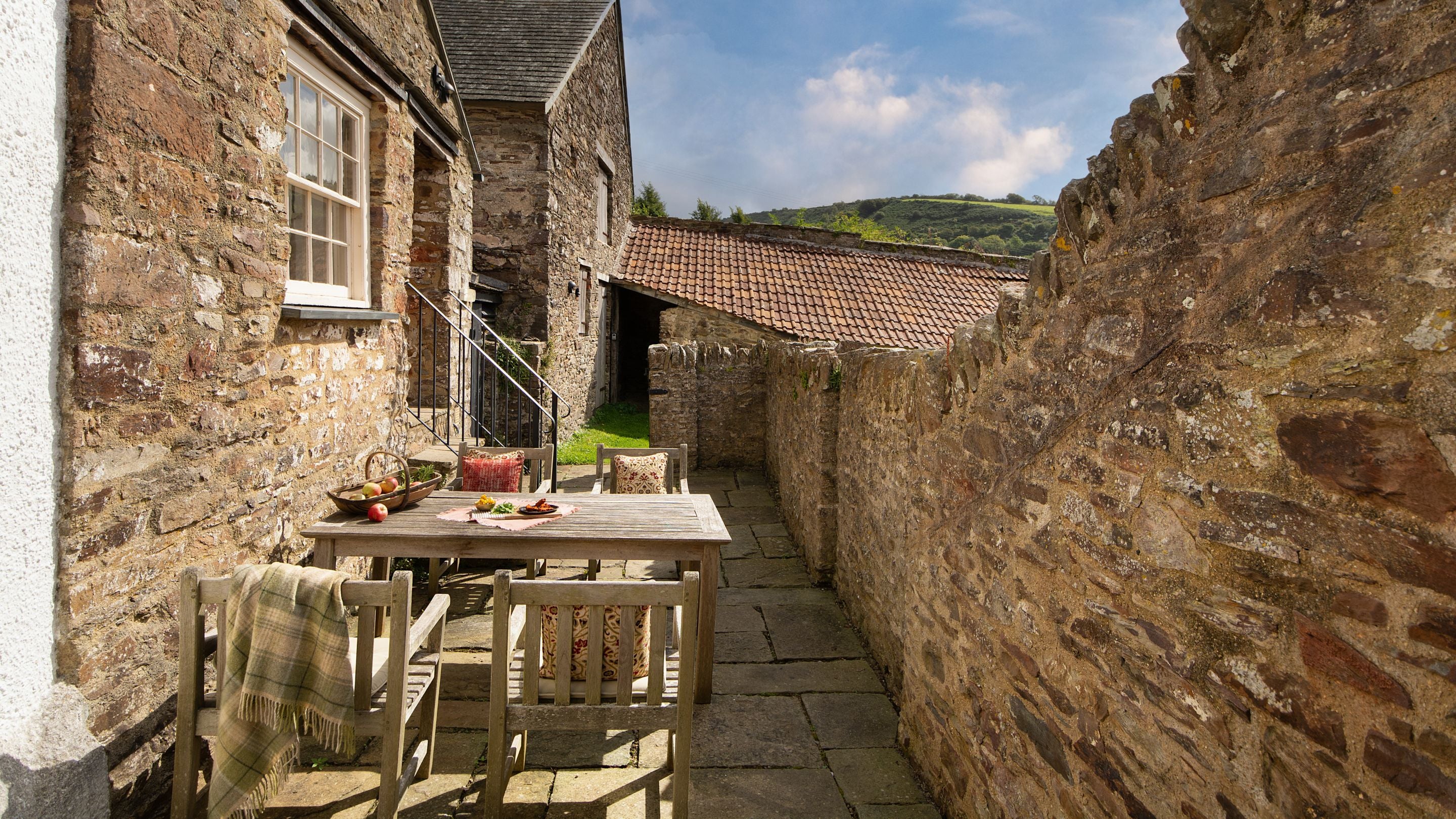 The terrace with outdoor dining furniture and main door to West Challacombe Manor, Devon