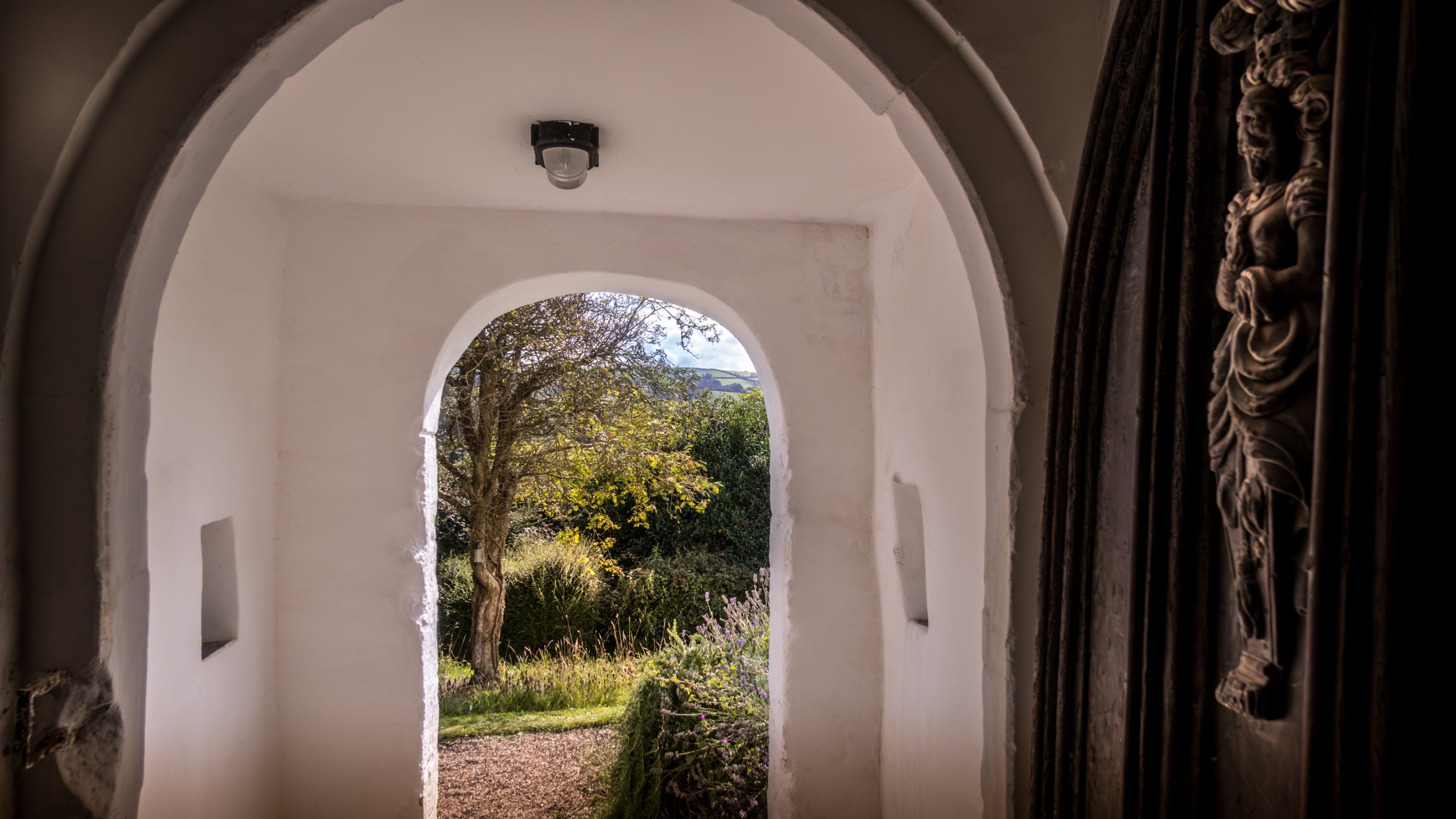 The view of the front garden through the historic door and porch from the hallway at West Challacombe Manor, Devon