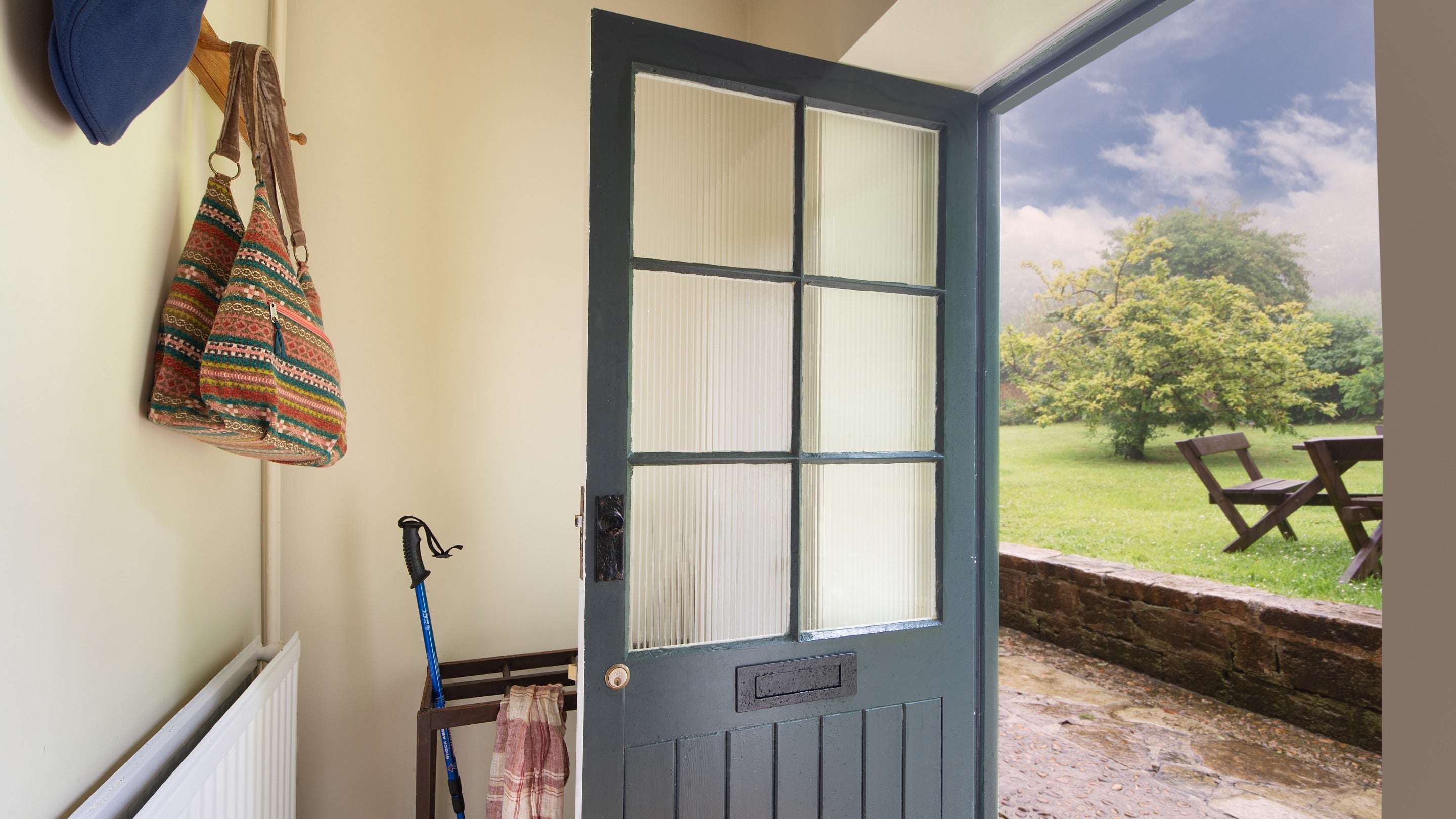 The entrance hall at Ash Cottage with the open door showing the raised garden lawn, trees and picnic table outside, Dorset