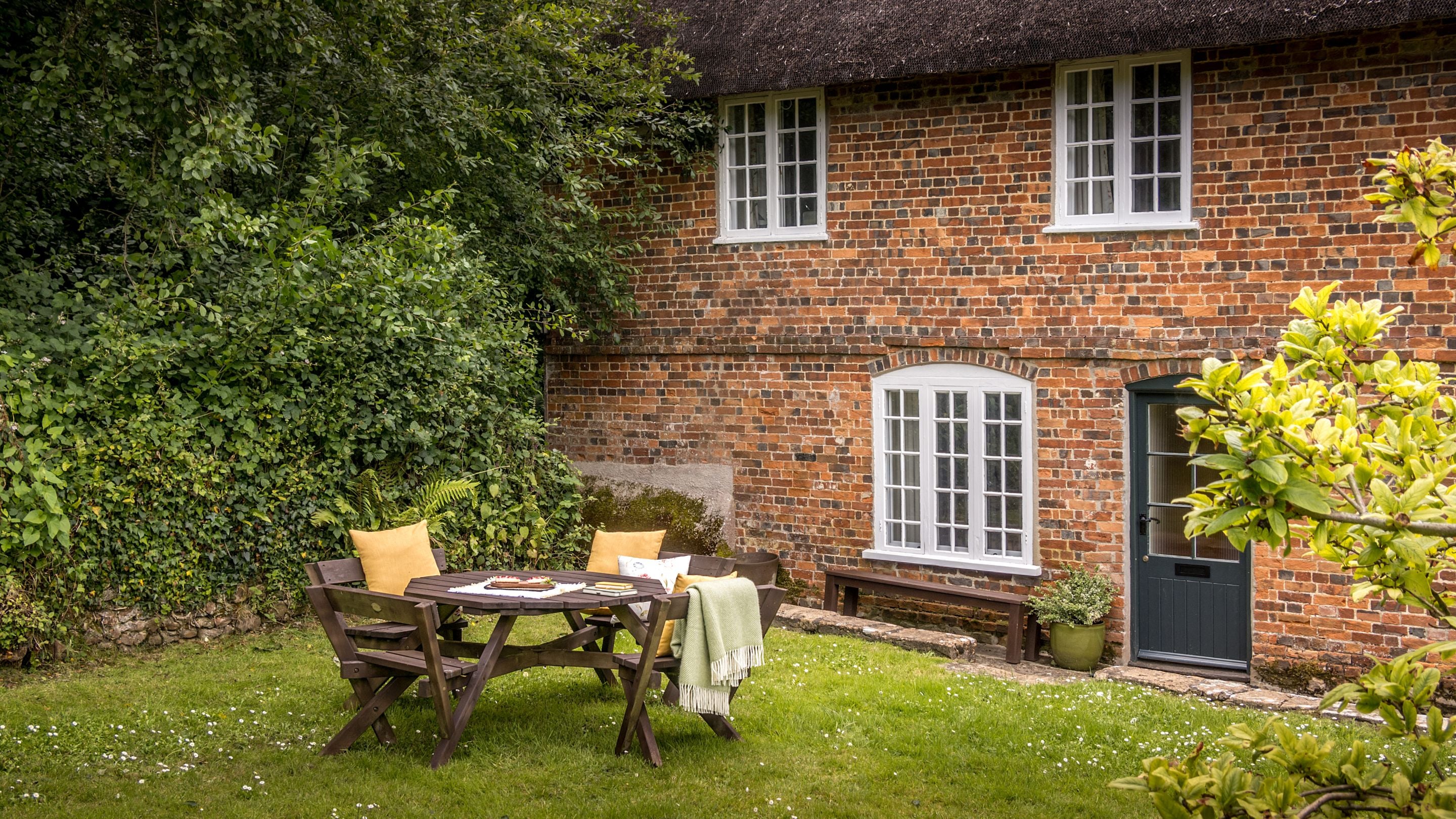 The exterior of Ash Cottage and its picnic table in the shared garden, Dorset