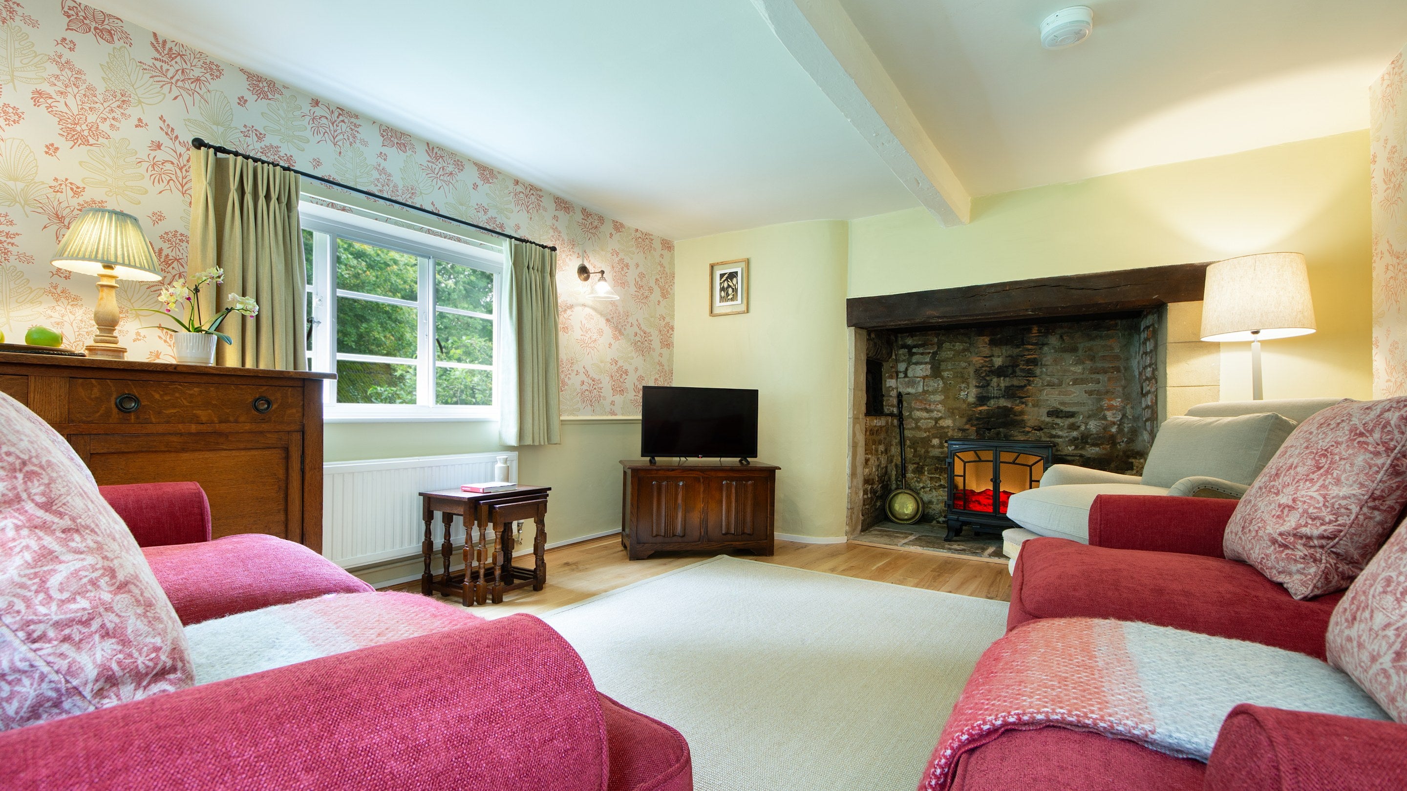 The sitting room with sofas, armchair, television and original inglenook at Beech Cottage, Dorset
