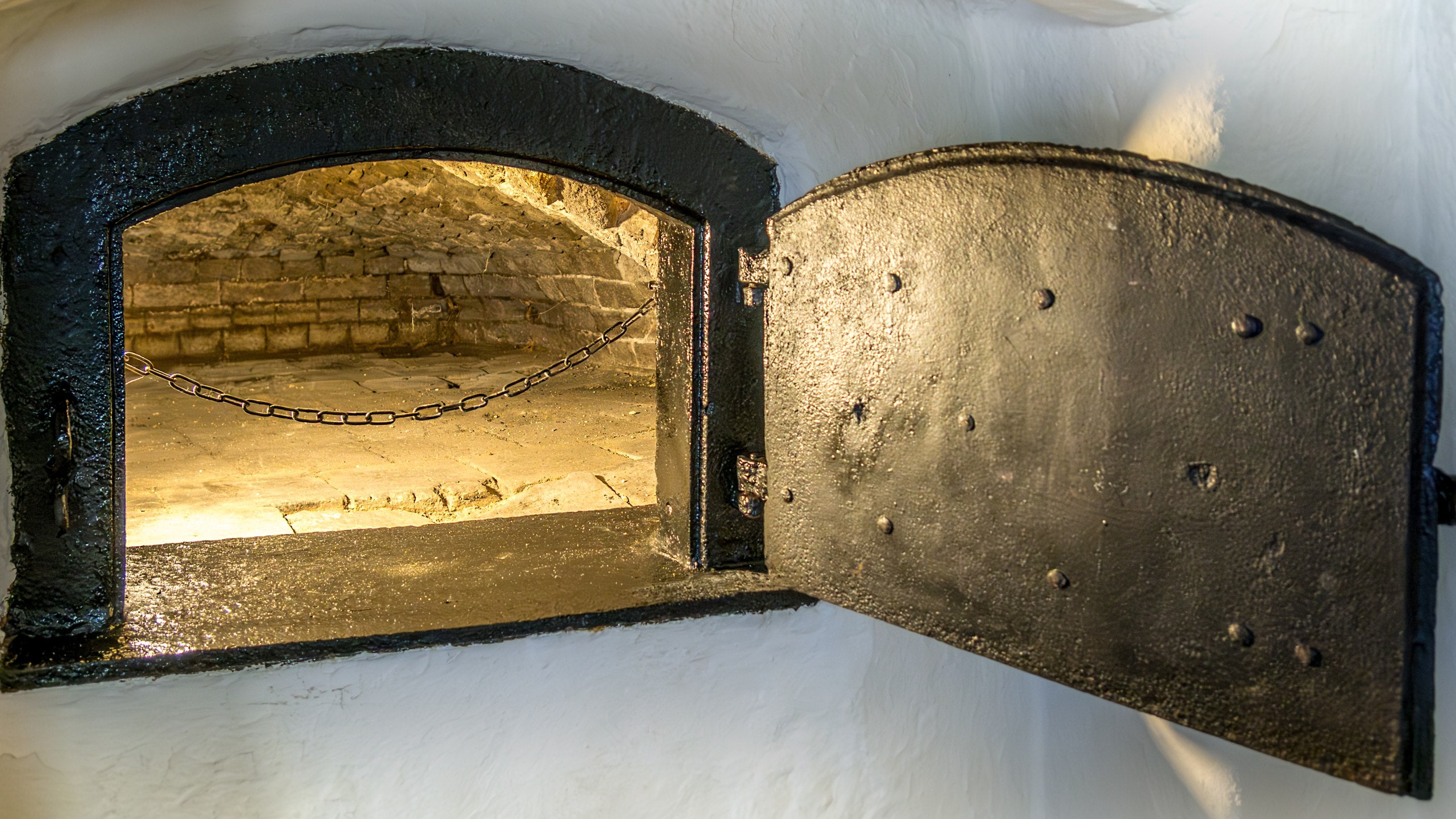 The open door of the original bread oven in the dining room of Boar Mill Cottage, lit up to show the interior stonework, Dorset
