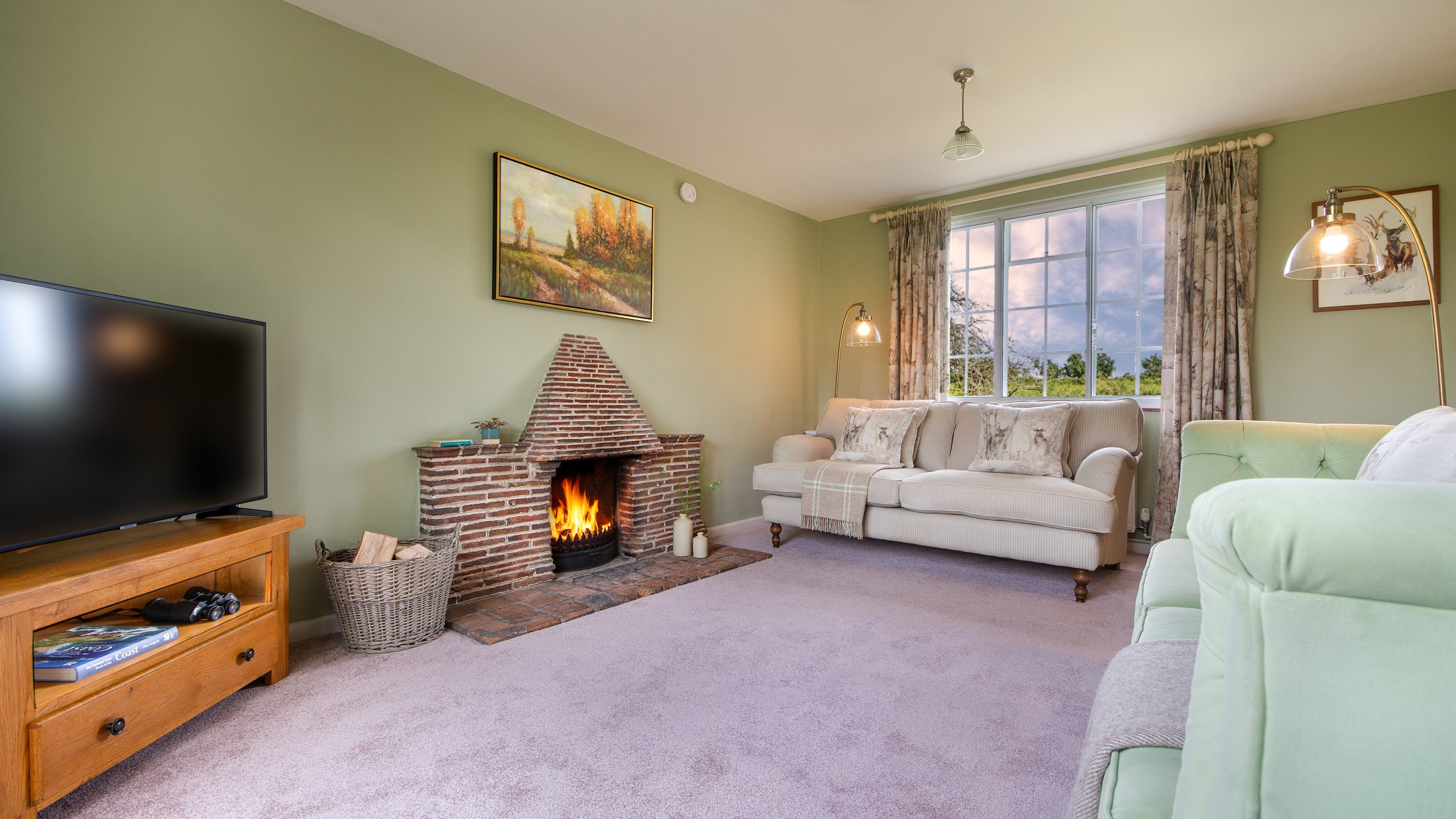 The sitting room at Greenlands, with fireplace, television and sofas, Dorset