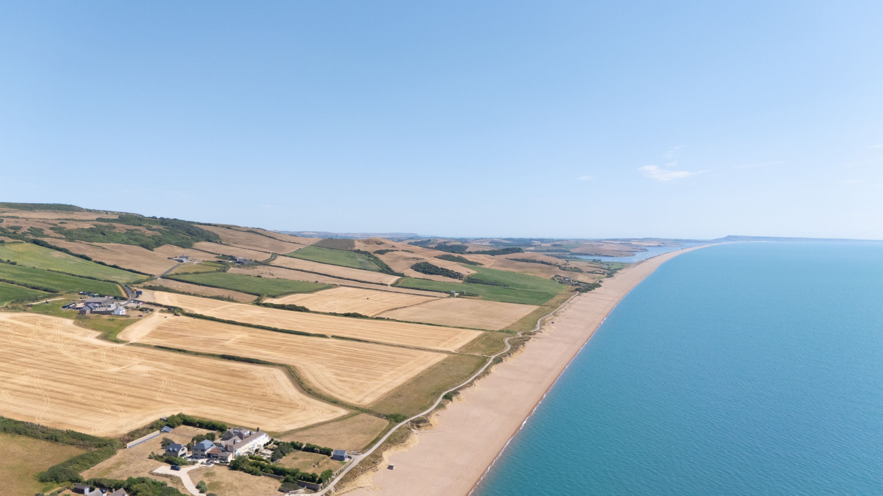 An aerial view of the coast and countryside by Labour in Vain Cottage and Chesil Cottage, Dorset