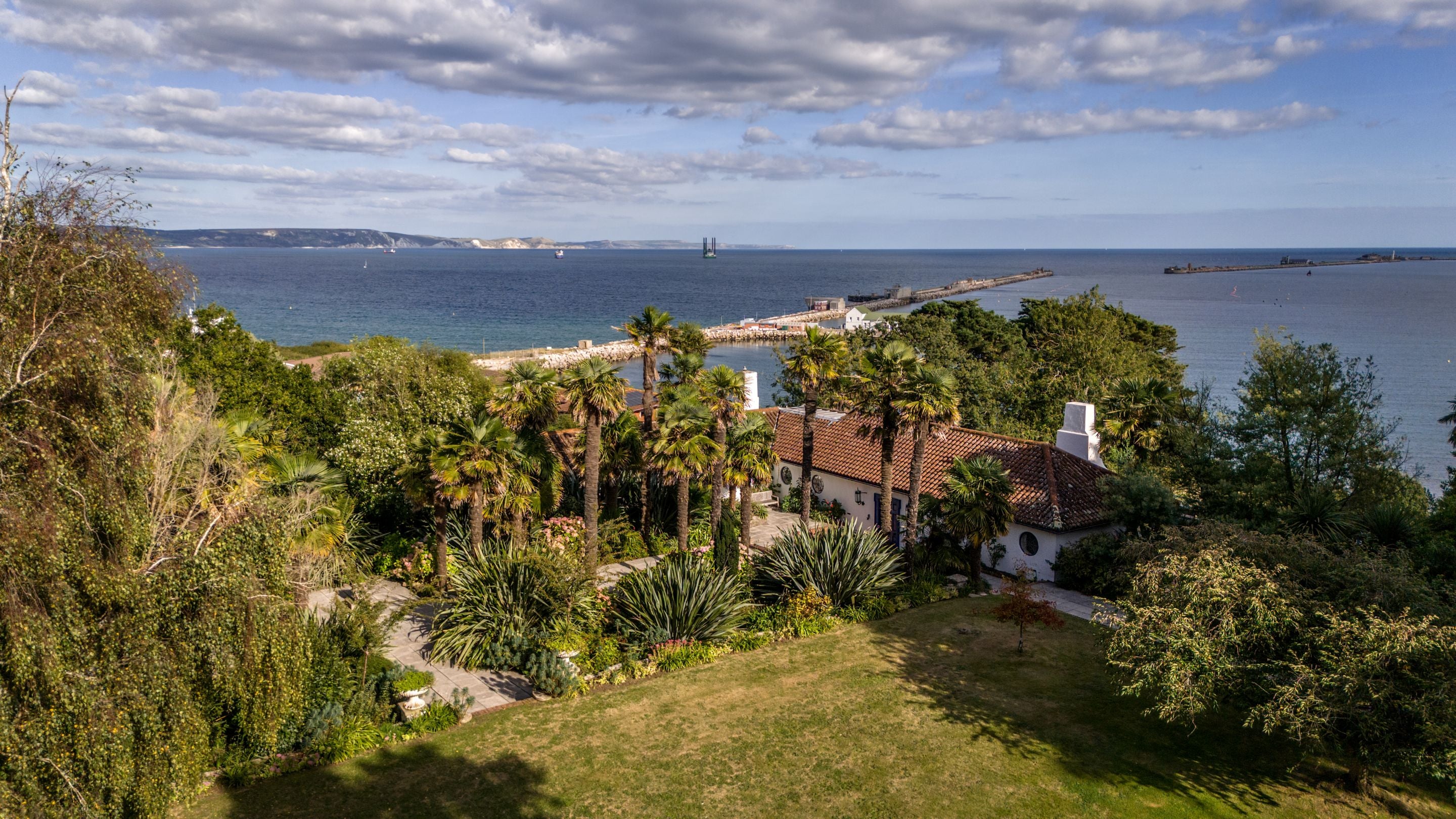 An aerial view of Portland House, its garden, the harbour and the Jurassic Coast in the distance, Dorset