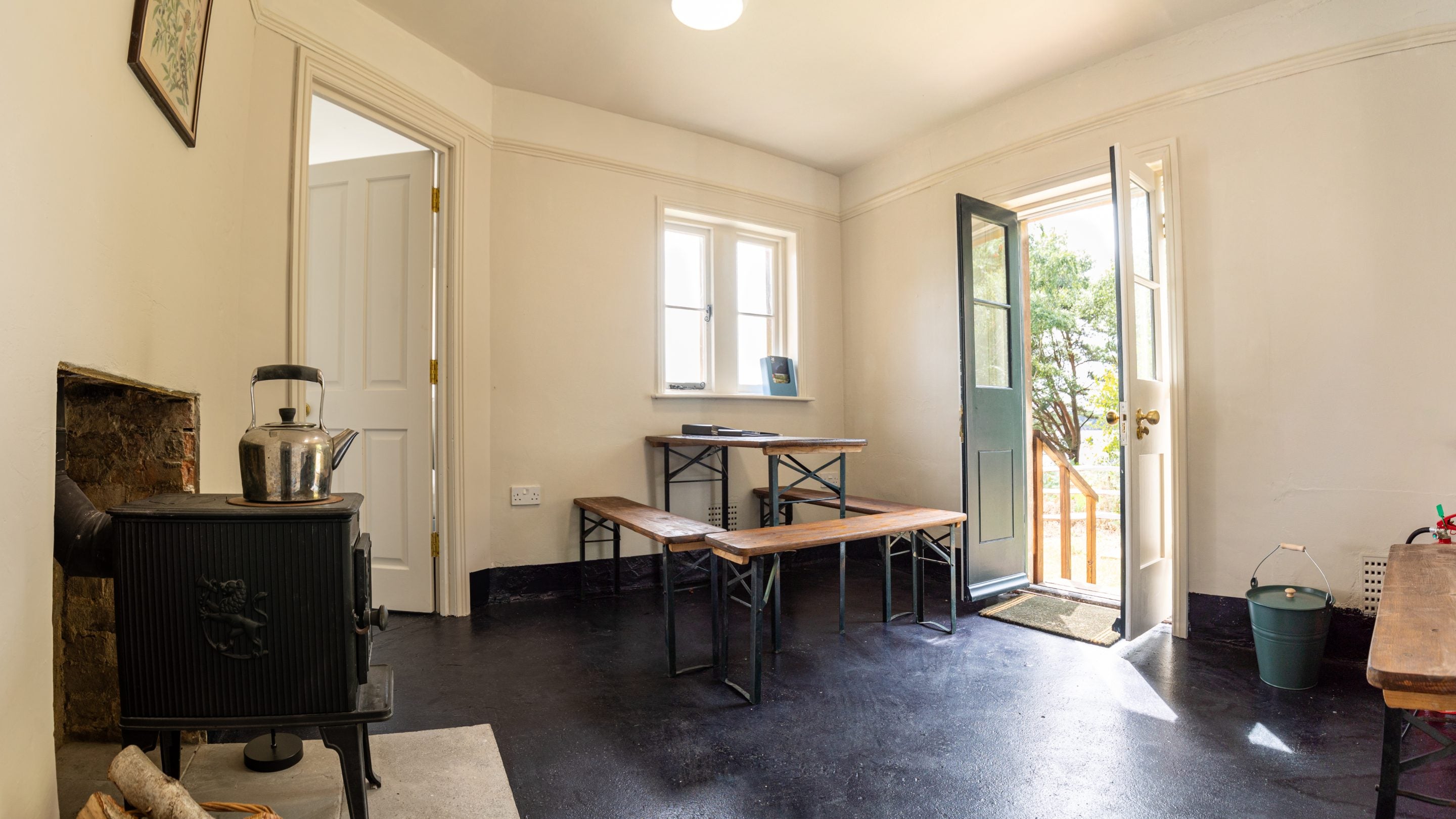 The room with woodburner, table and benches at St Mark's Bothy, Brownsea Island, Dorset
