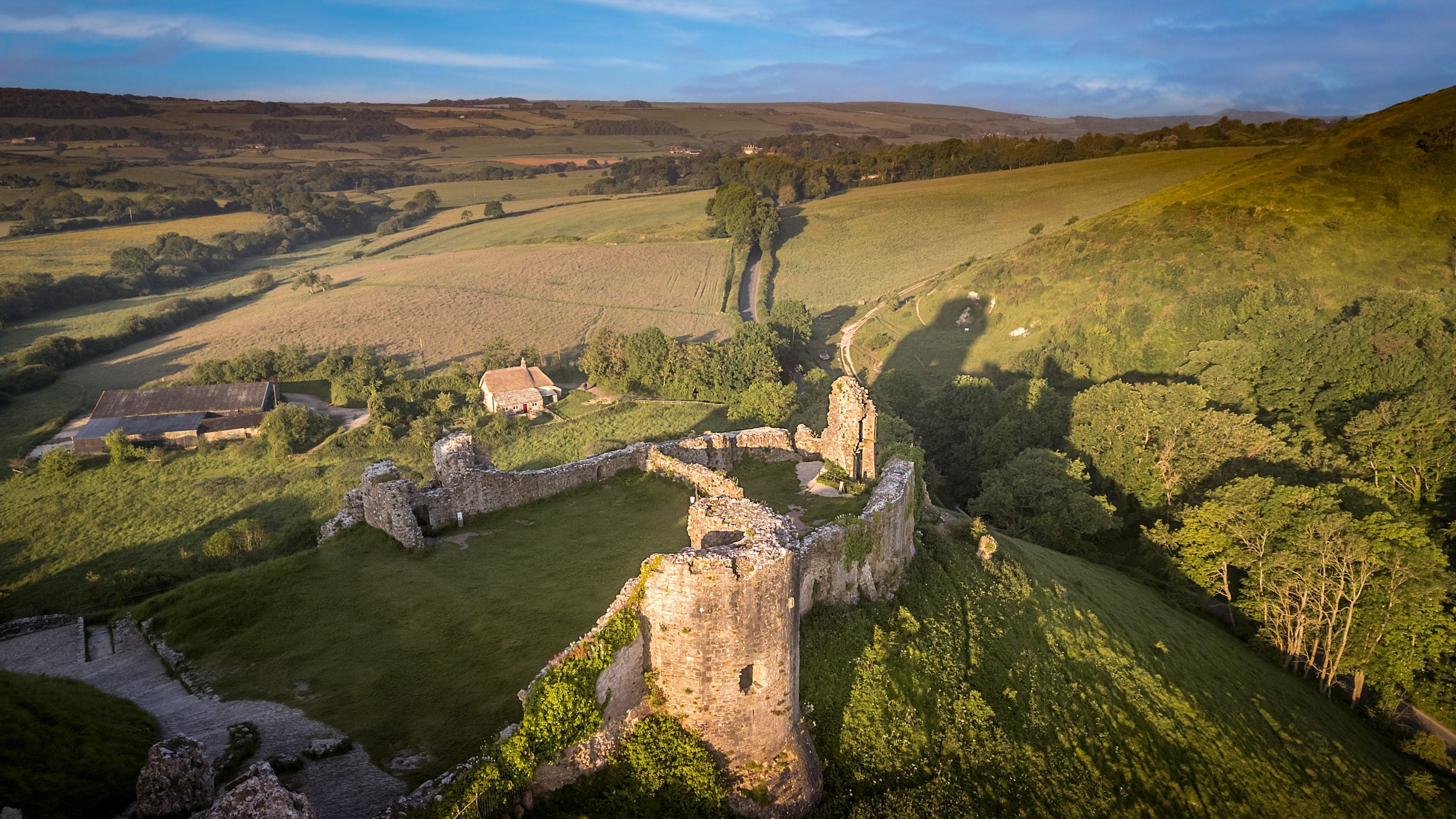 An aerial view of the ruins of Corfe Castle with Vineyard Farm Cottage in the background, Dorset