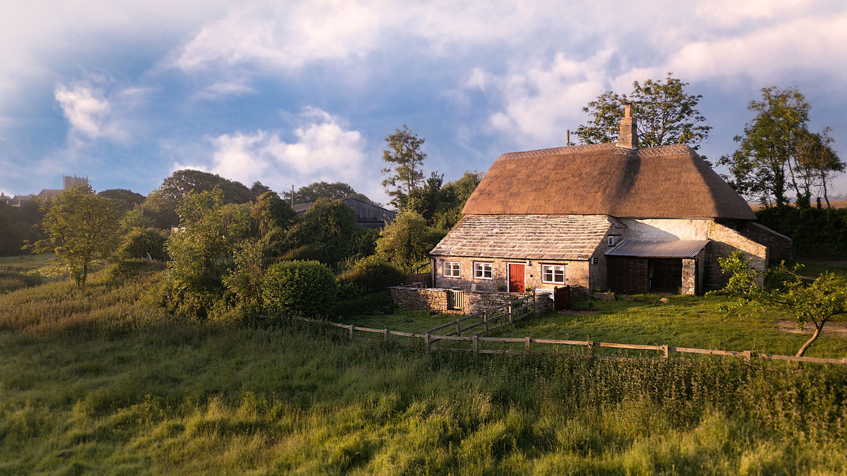 The exterior of Vineyard Farm Cottage, a stone cottage with thatched roof, Dorset
