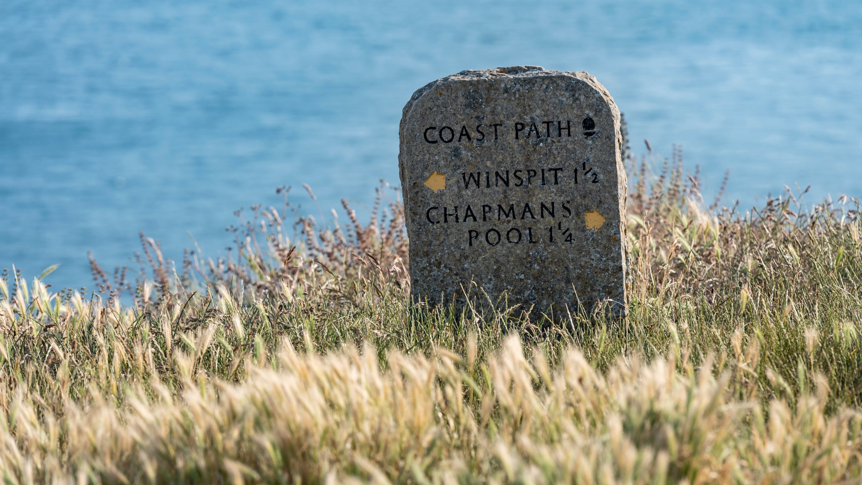Footpath sign near Weston Farm Campsite, marking the South West Coast Path and showing the routes to Chapman's Pool and Winspit quarry, Dorset